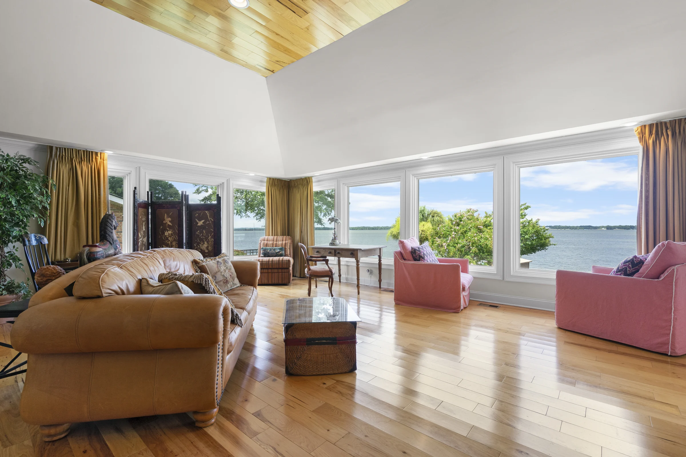 Living room with couches and a desk facing a large lake-view window