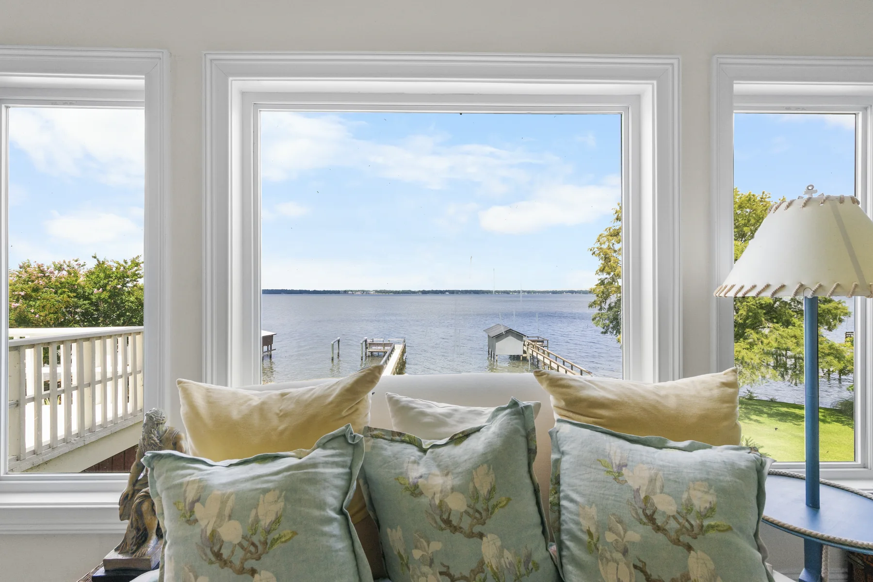Living room with a large window framing a lake and dock view