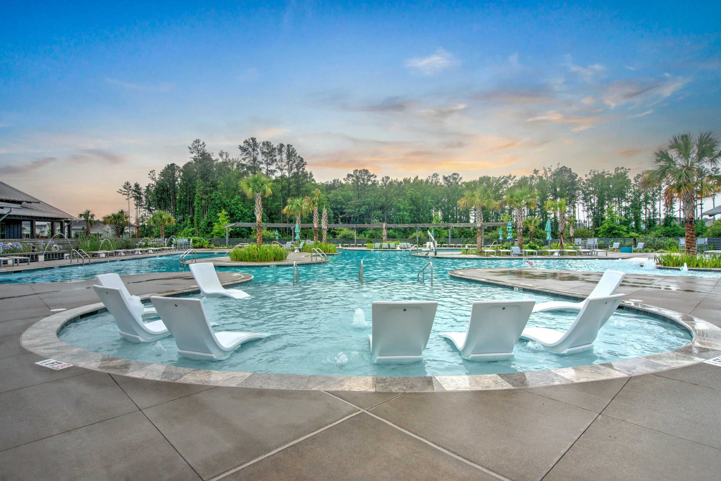 Aerial drone photo of a resort-style pool with lounge chairs and palm trees at sunset