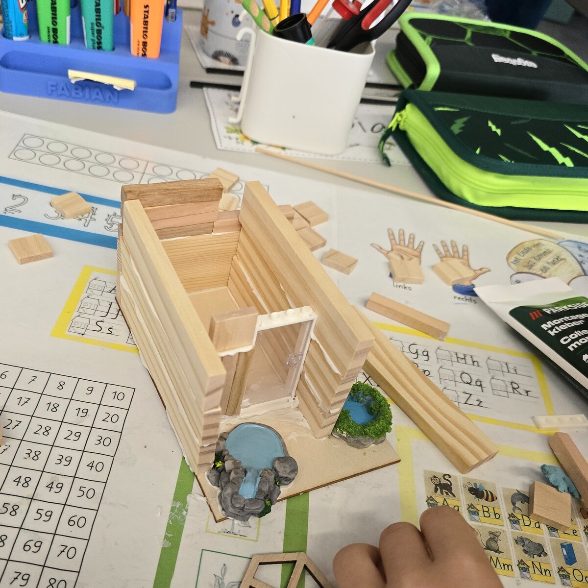 Hands building a small wooden house