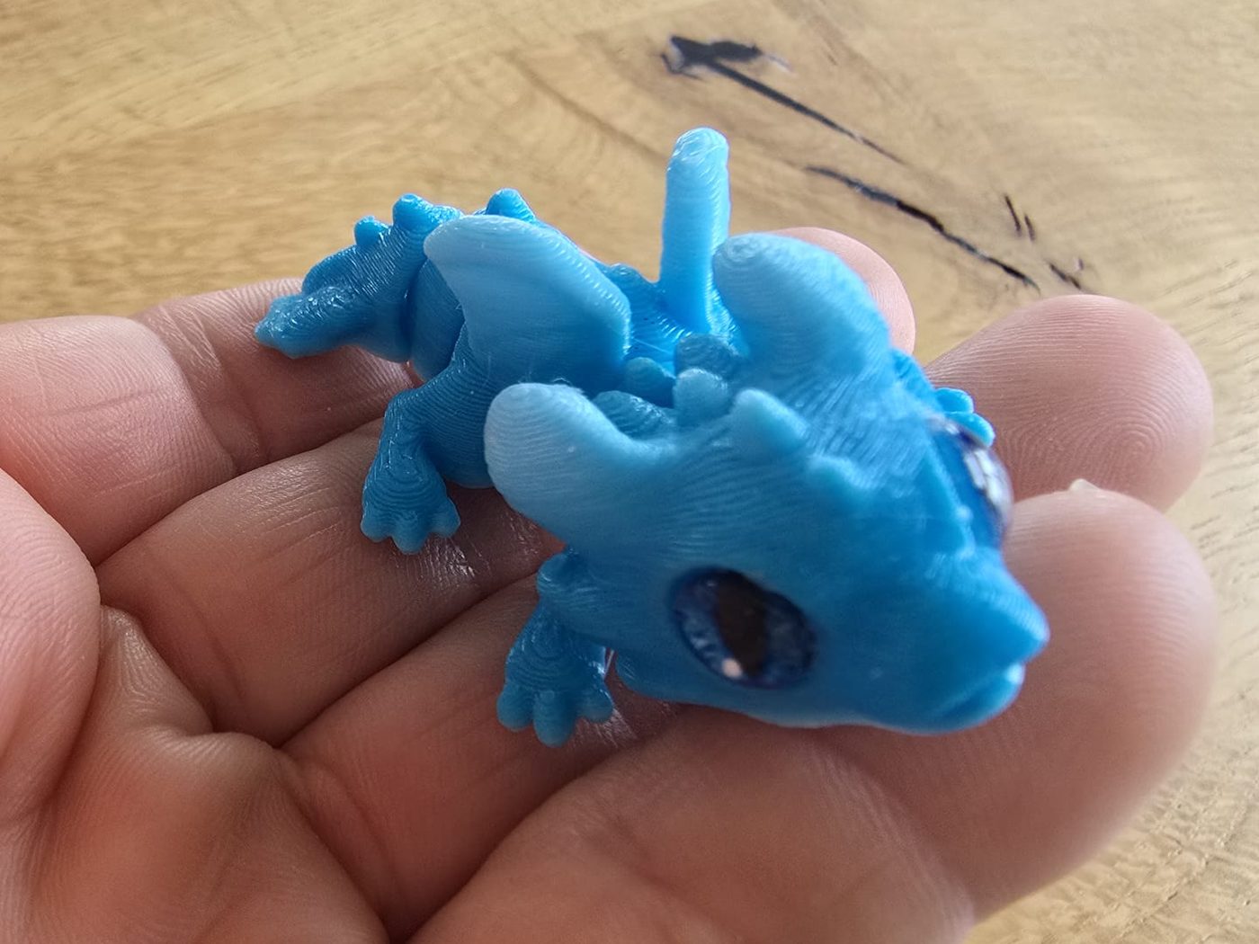 Ein kleiner blauer Glücksdrache S liegt in einer Hand