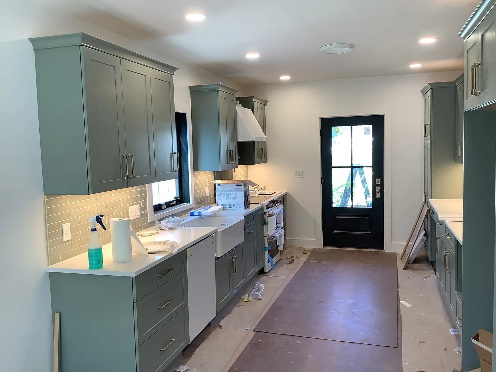 Kitchen remodel with recessed ceiling lights, gray cabinets and protected flooring