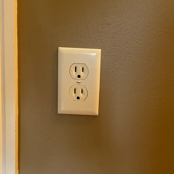 A white three-slot duplex receptacle installed on a residential wall
