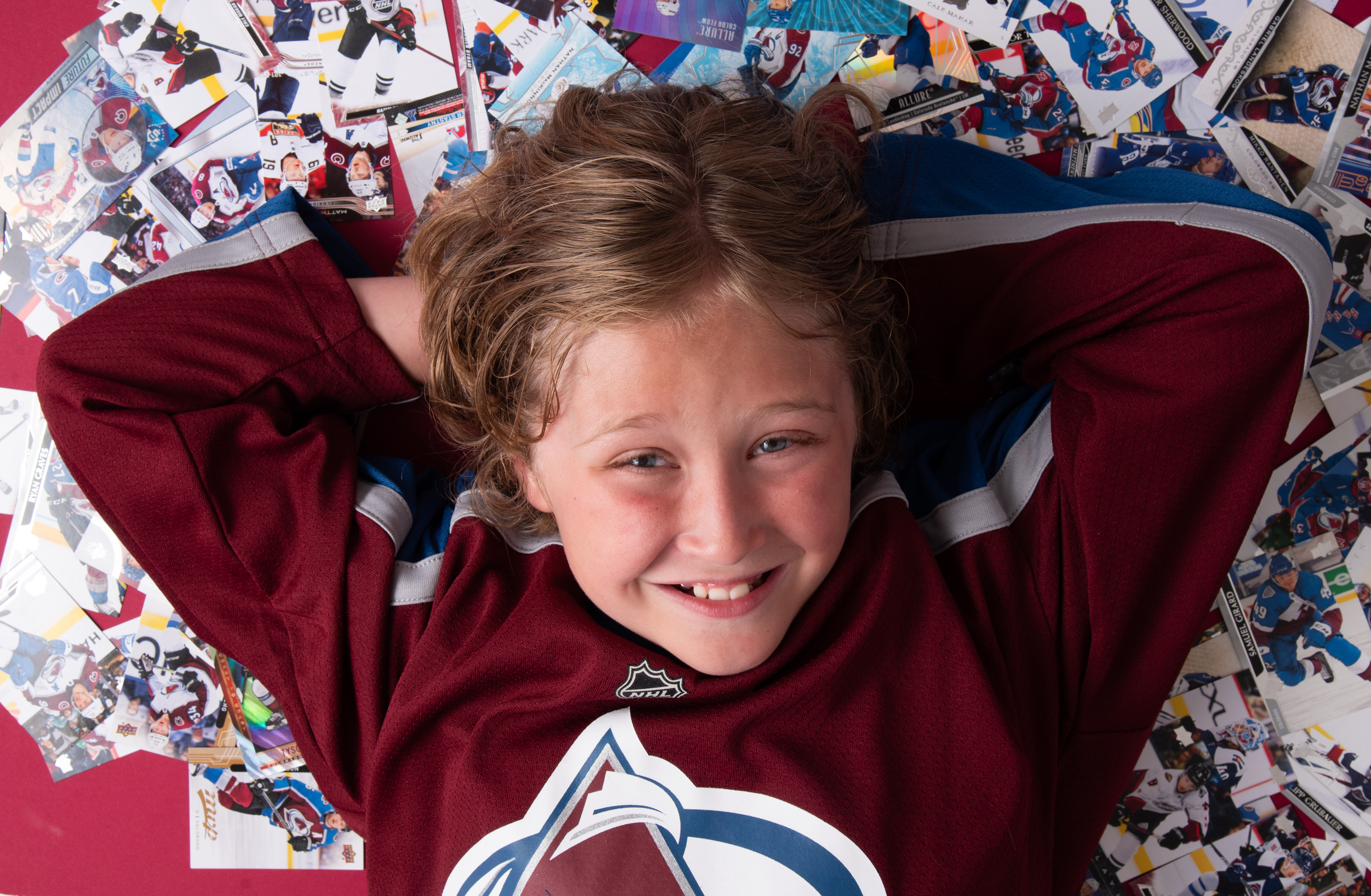 10 year old smiling while laying on Colorado Avalanche playing cards