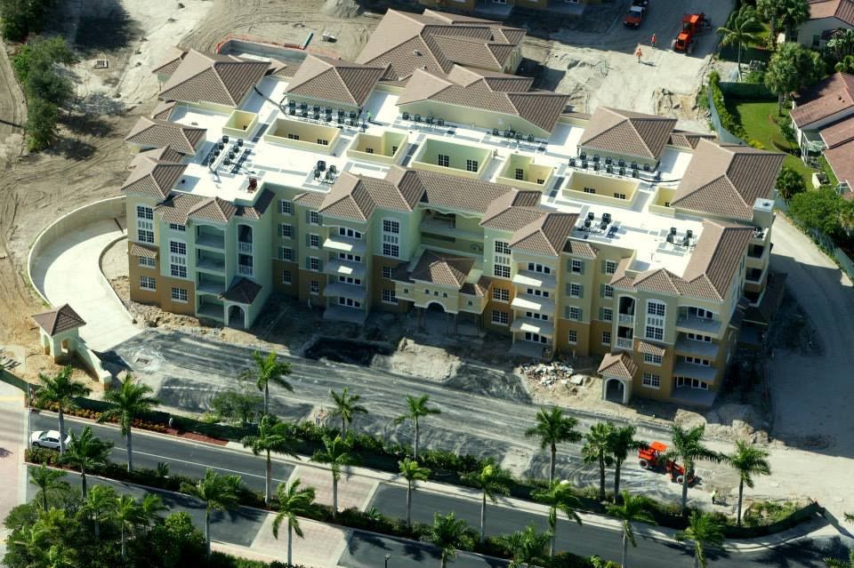 Mid-rise condominium building under construction with tile and flat low-slope roof sections