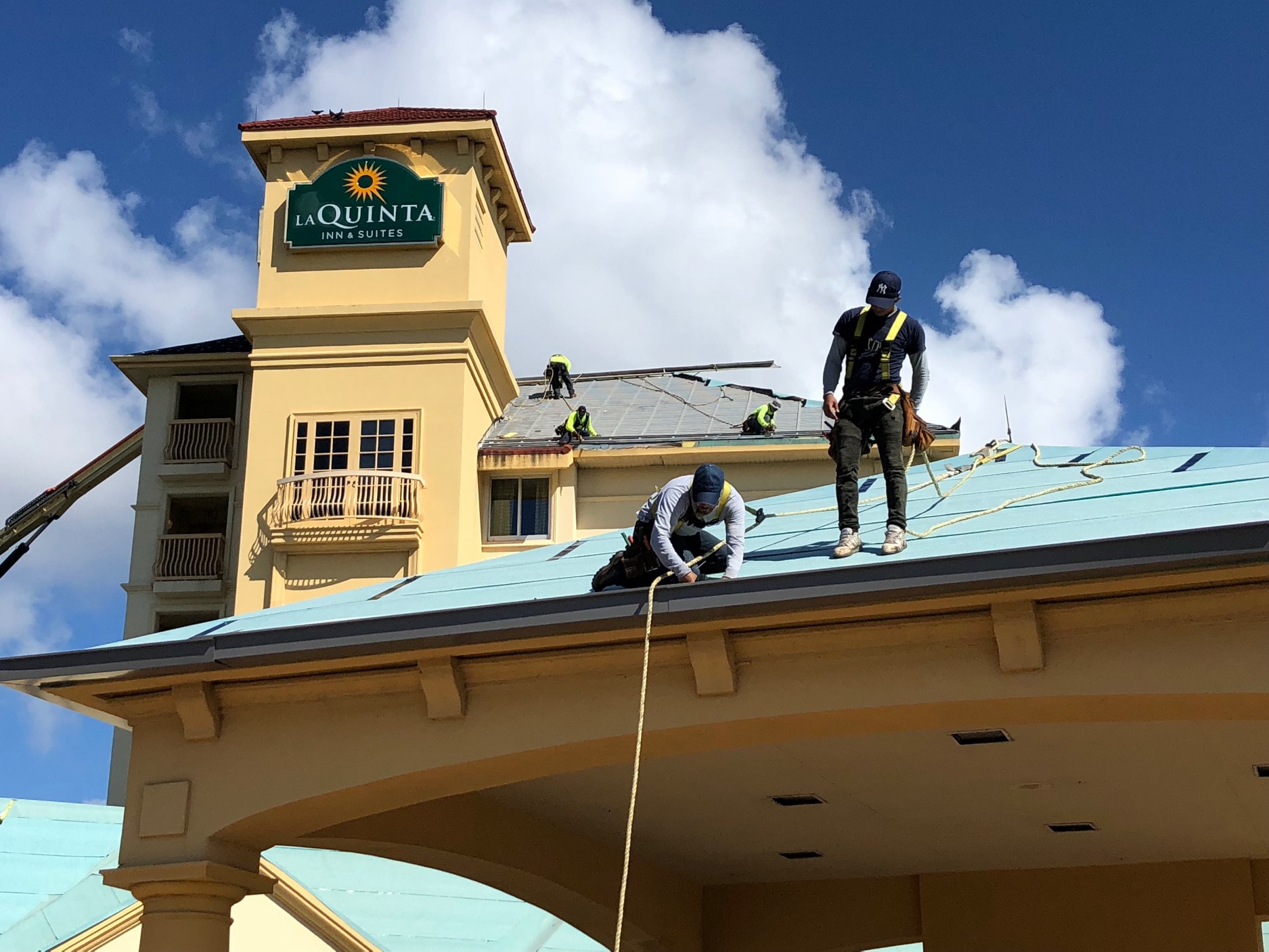 Crew installing standing seam metal roofing on a hotel