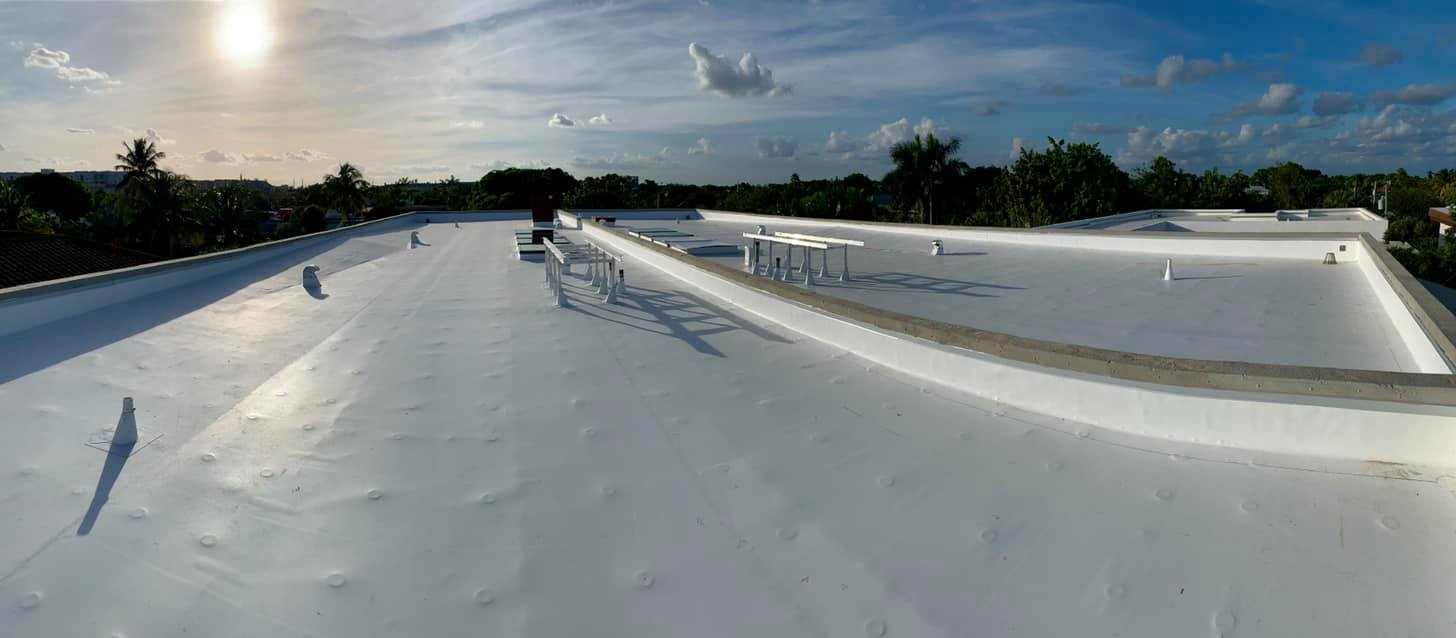 Flat roof with a newly applied white coating under a clear sky