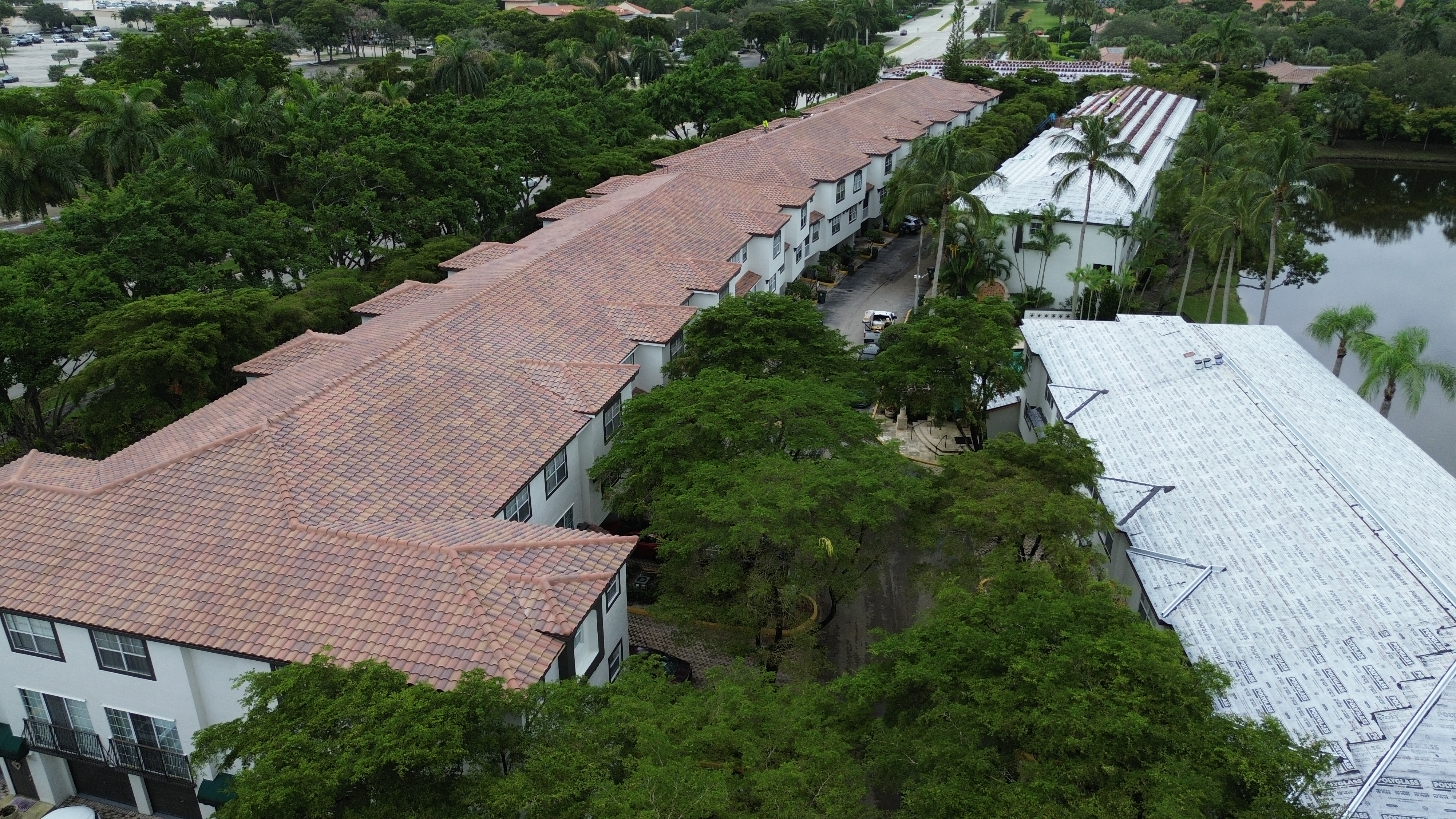 Aerial view of a multi-building community re-roof, with new underlayment on one building and tile on the others
