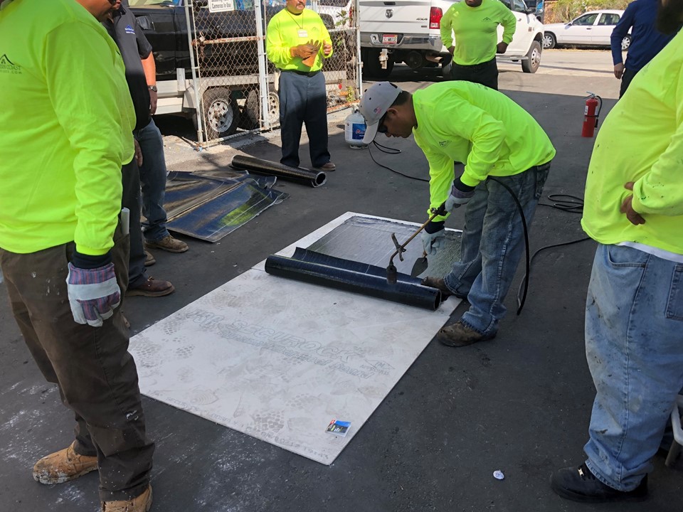 Crew member applying roofing material during group training