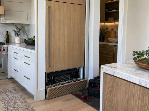 Panel-ready refrigerator column photographed after service in a customer kitchen