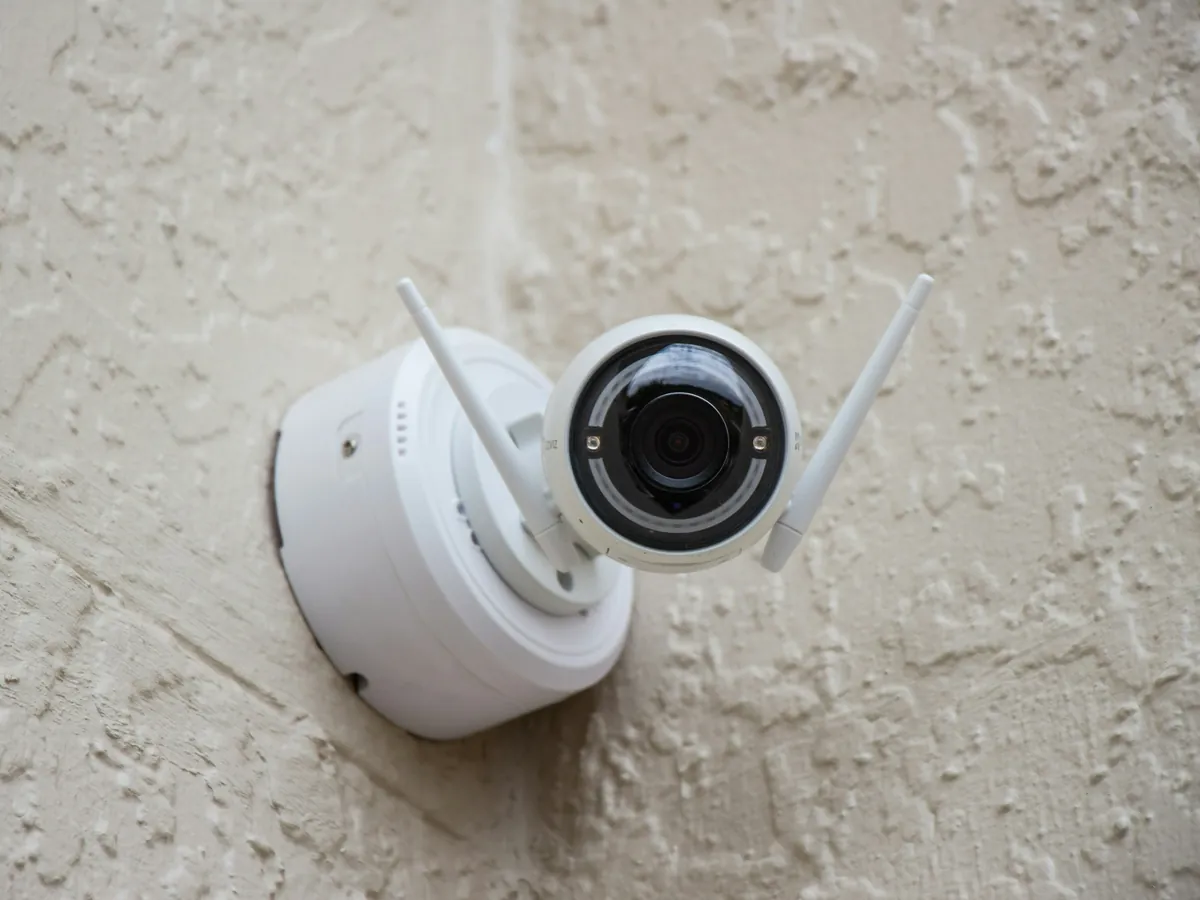 White dome security camera fixed to a rendered wall