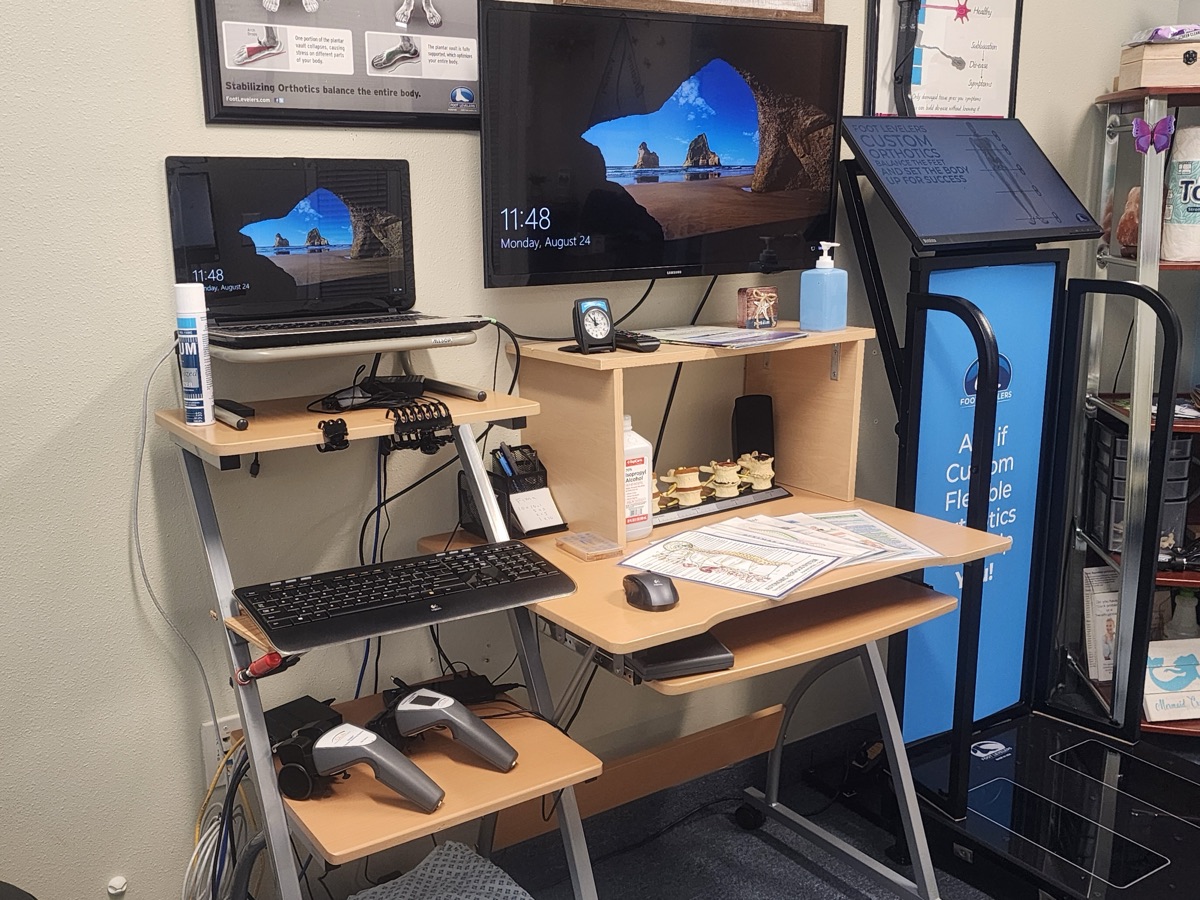 The exam room technology Dr. Tom uses to assess patients, with spine models and scan reports on the desk