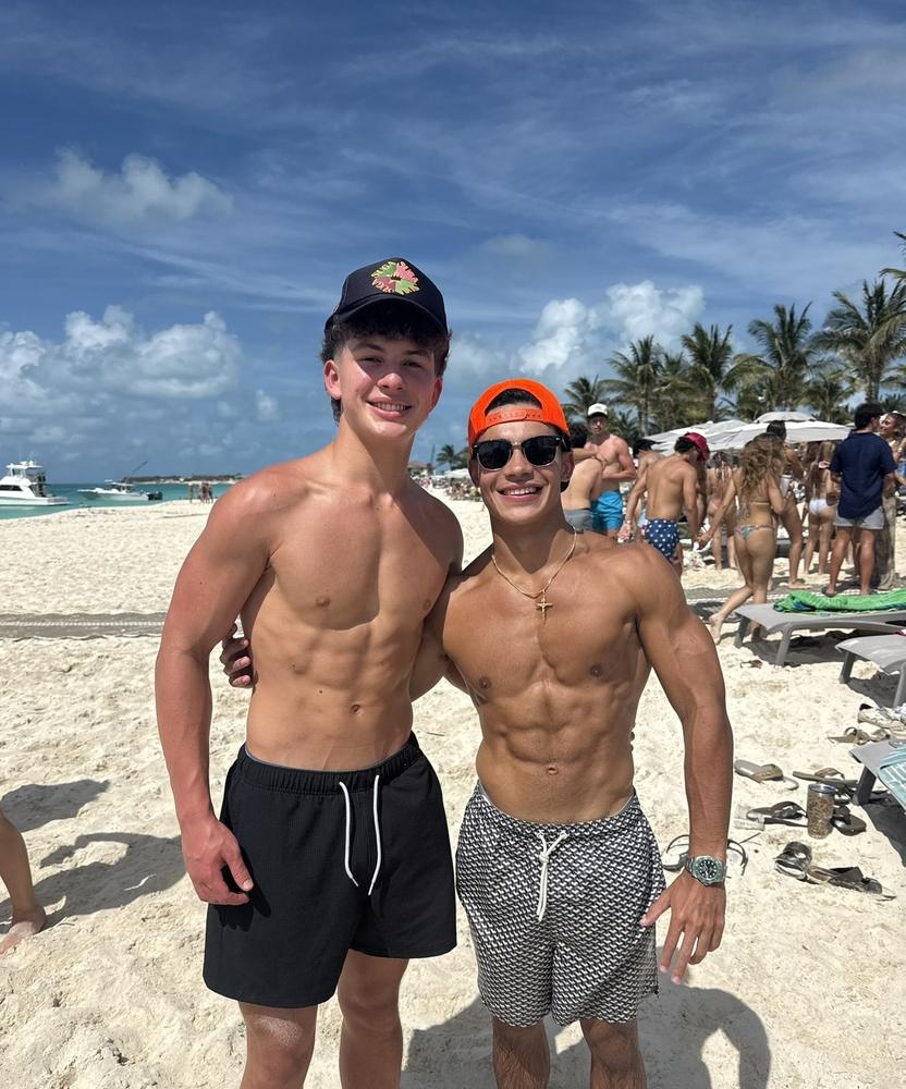 Sergio with a coaching client on the beach, both showing lean physiques