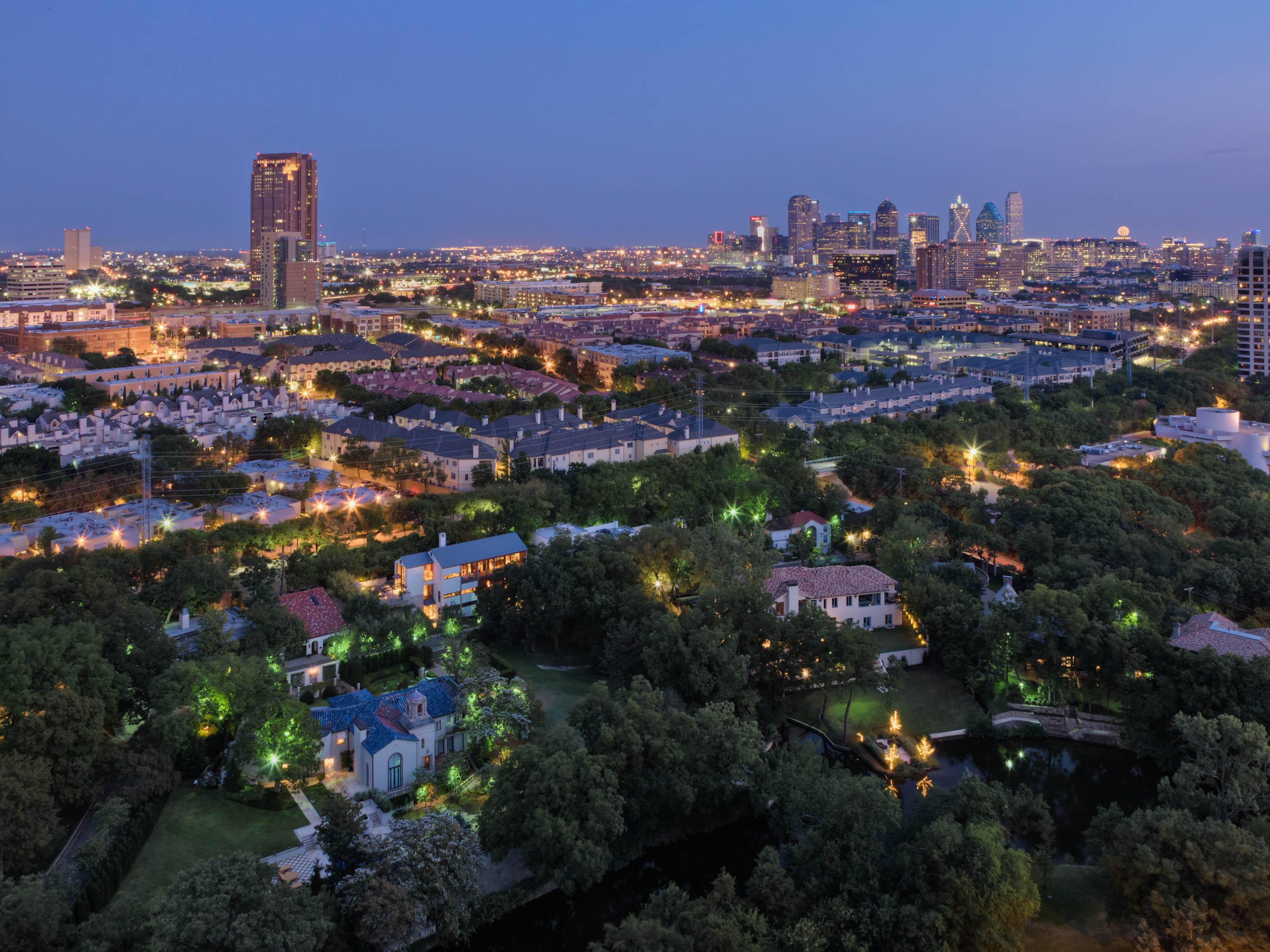 Tree-filled neighborhood at dusk with the skyline in the distance