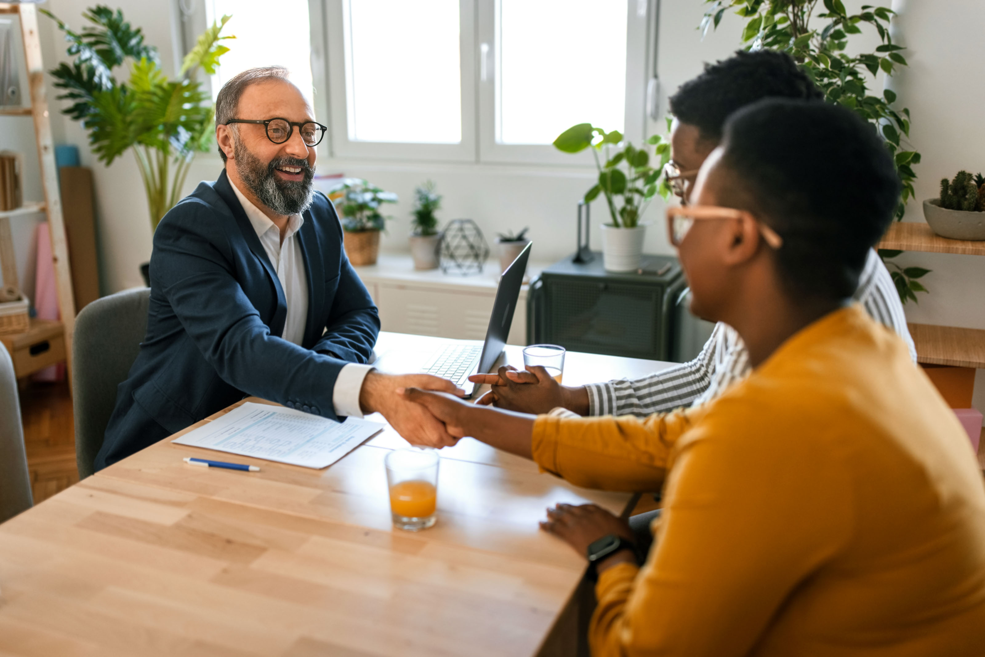 Bearded man in a navy blazer shaking hands across a table