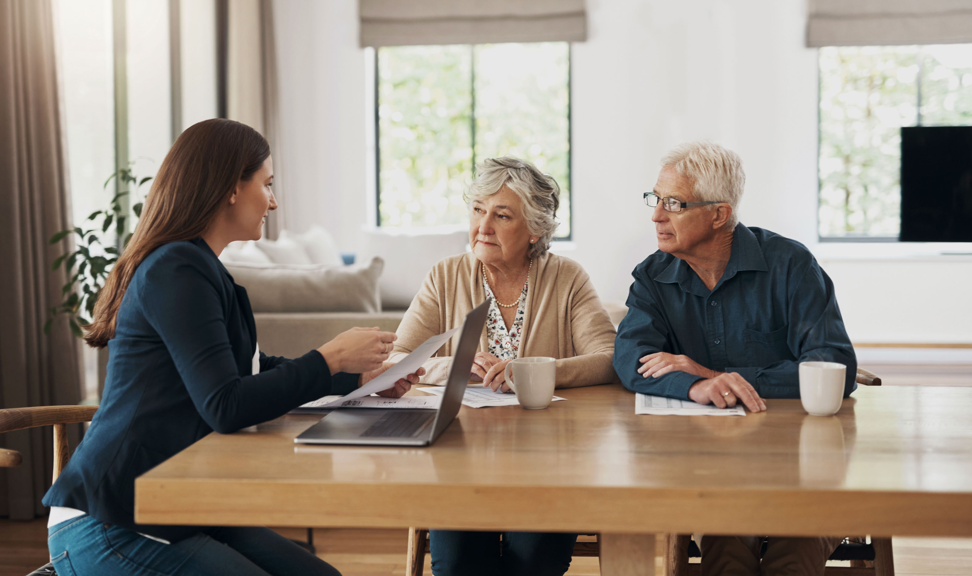 Adviser presenting documents to a senior couple at a dining table
