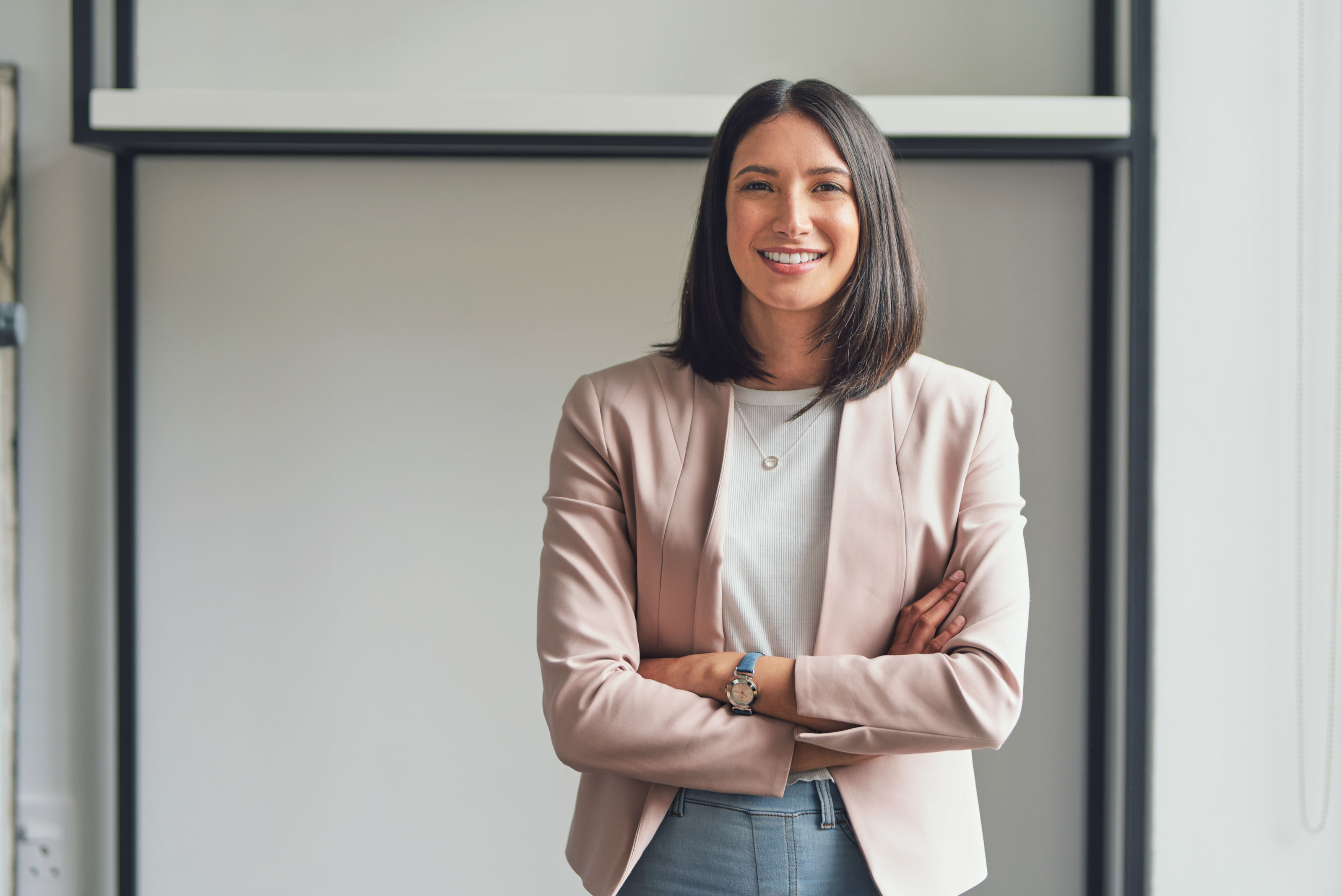 Woman in a blush blazer standing with arms folded