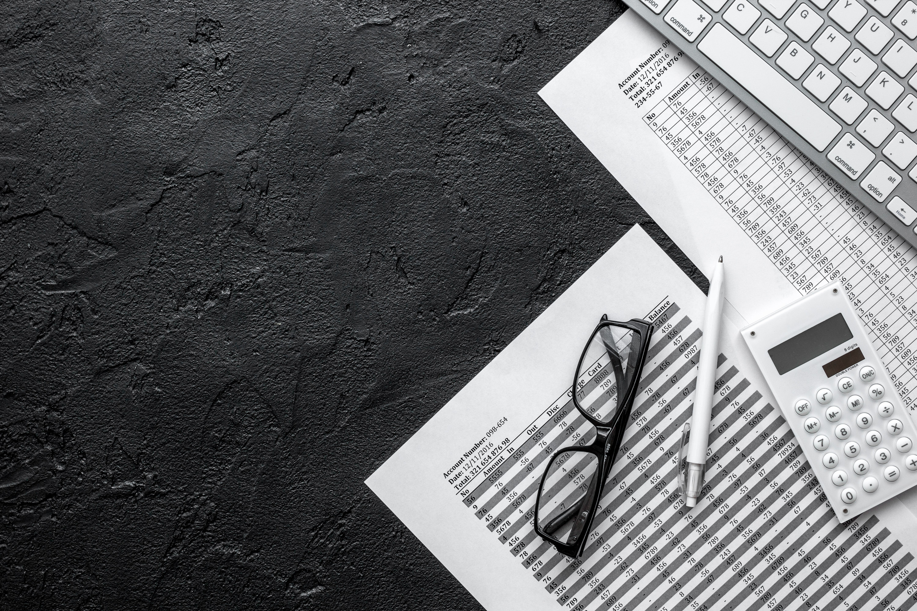 Flat-lay of printed statements, glasses and a white calculator