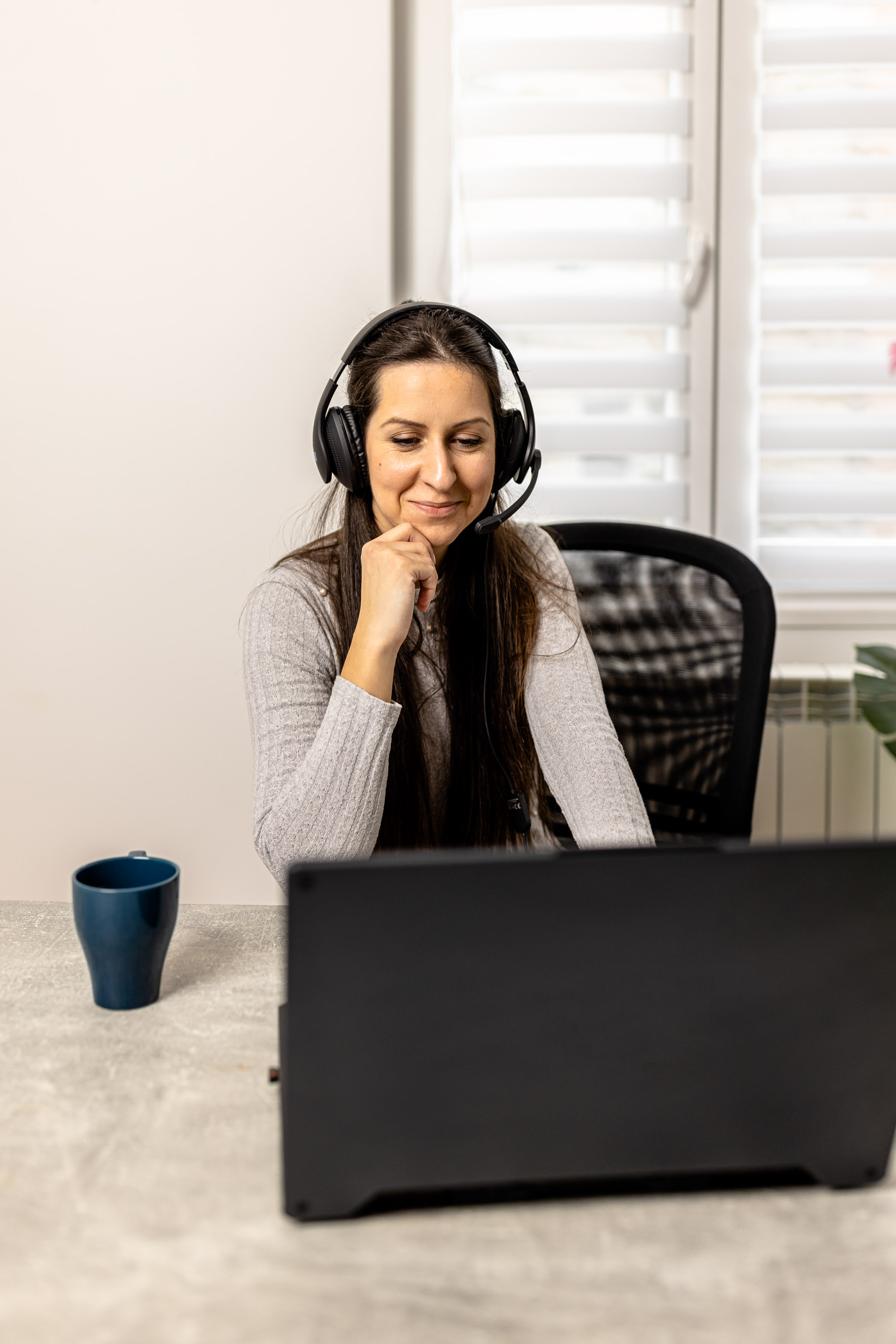Woman in gray cardigan with a headset resting her chin on her hand