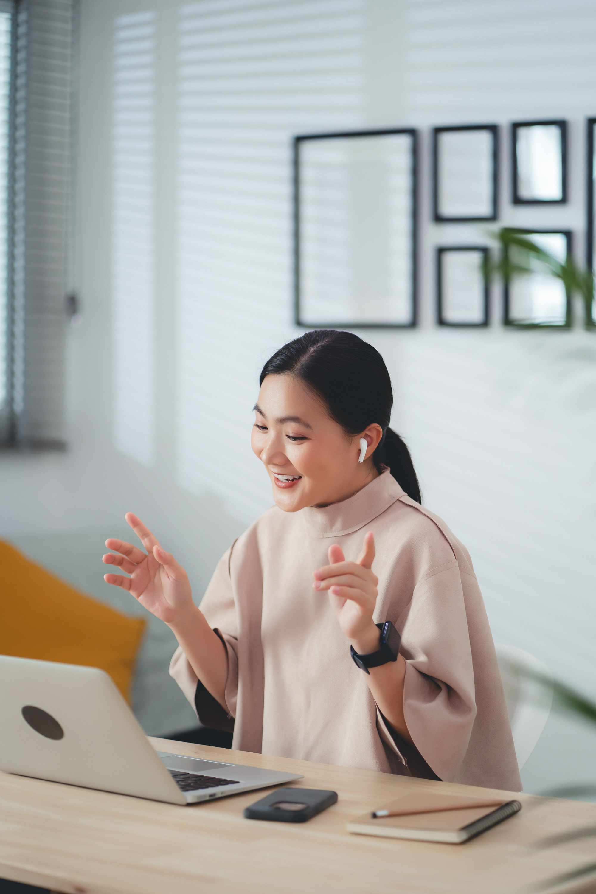 Woman in blush top gesturing during a laptop video call