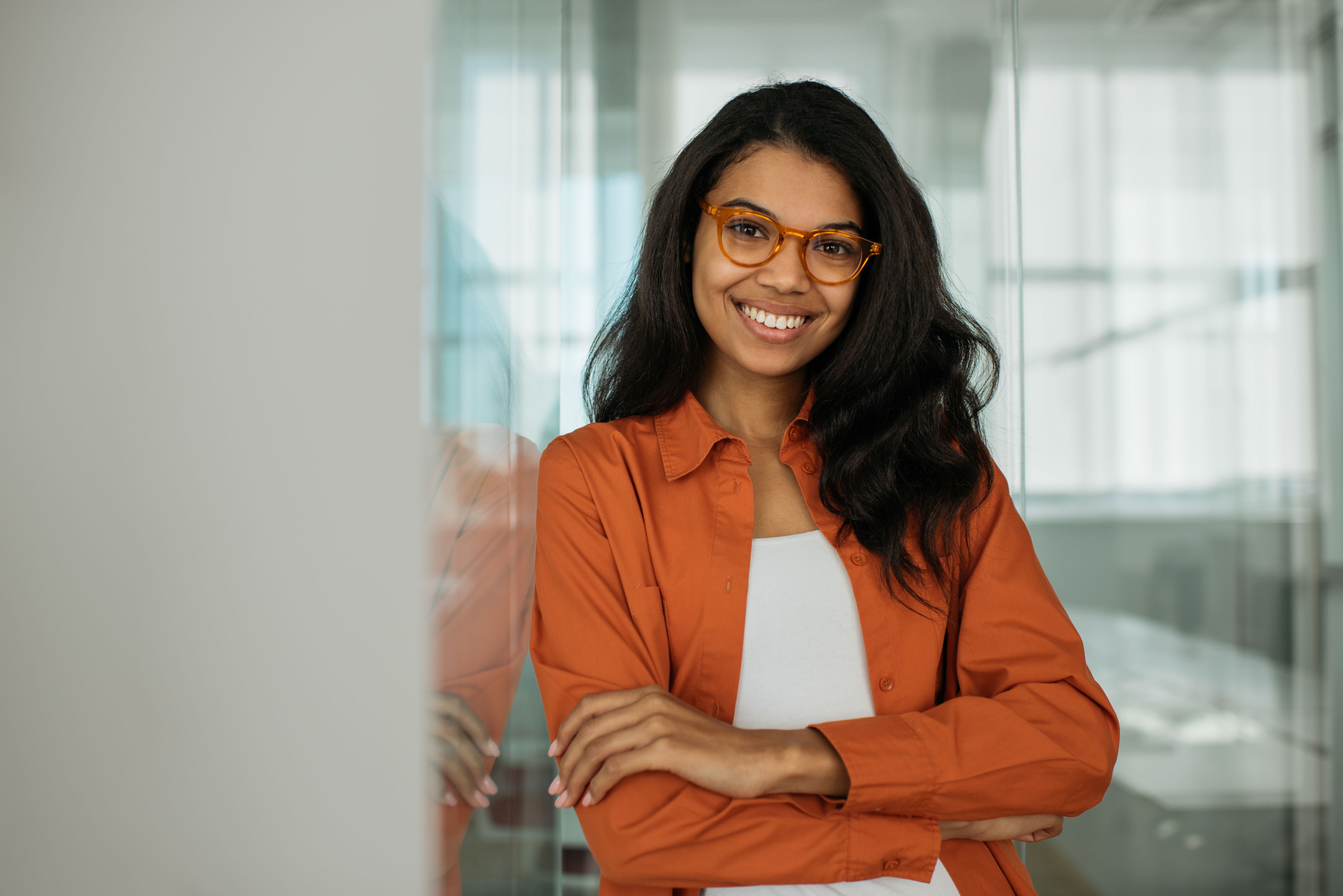 Young woman in rust-orange shirt with arms crossed