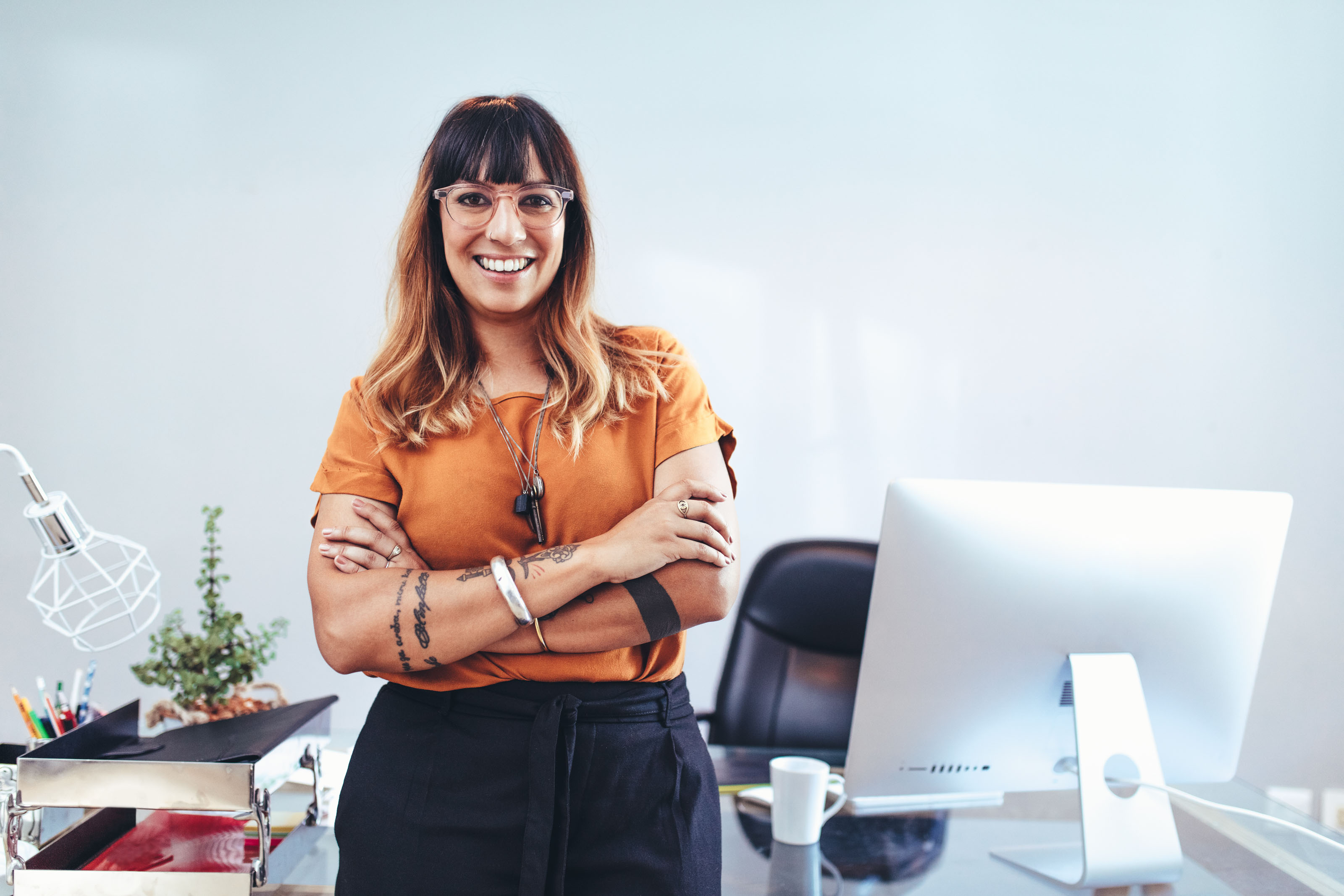 Smiling tattooed woman with arms crossed in an office