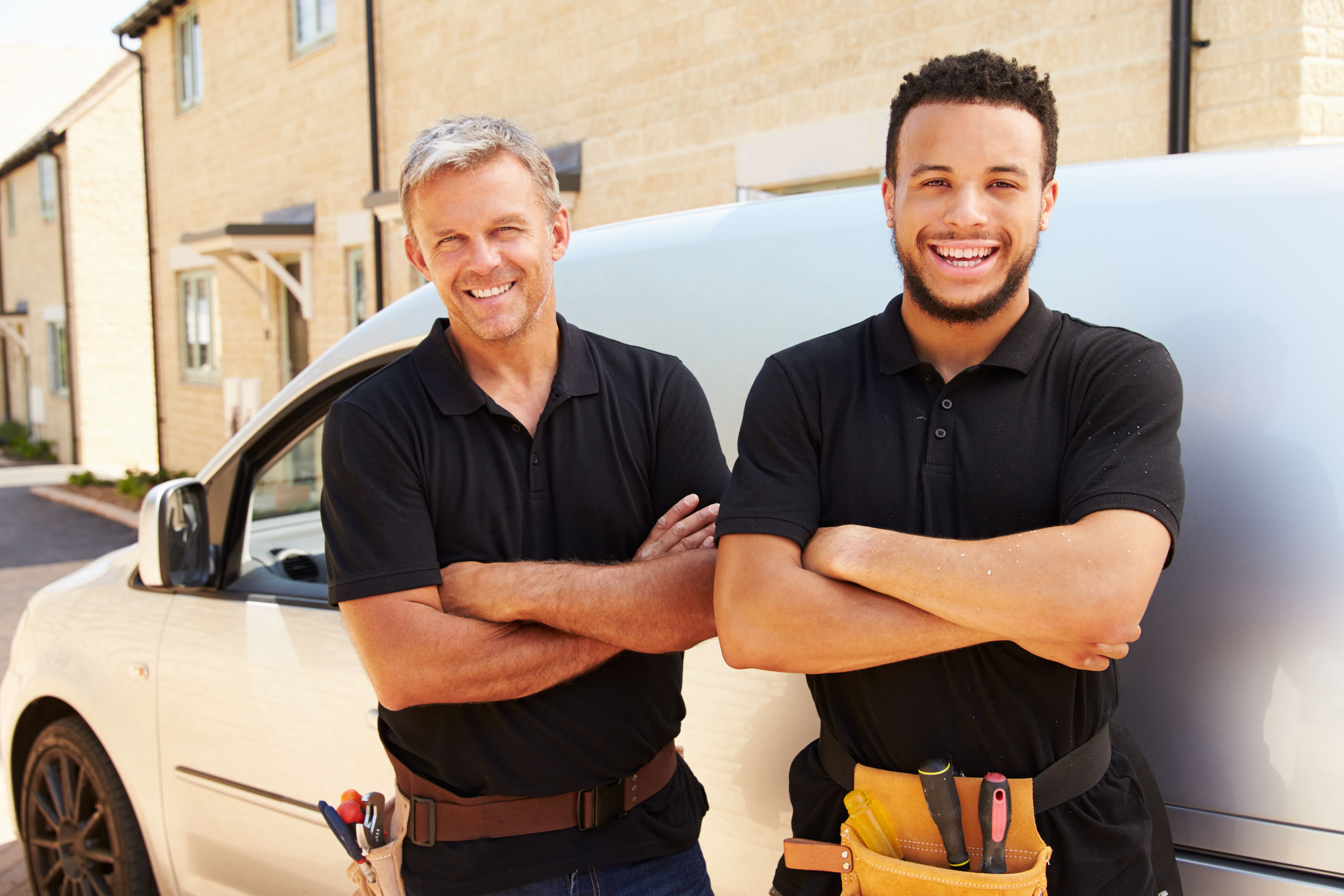 Two tradesmen with folded arms in front of a white work van