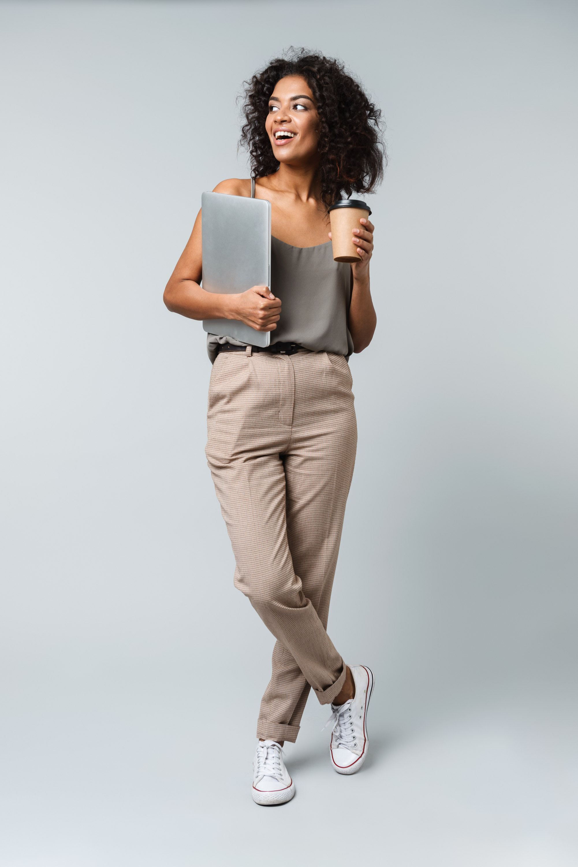 Woman walking with a laptop under her arm and a coffee cup