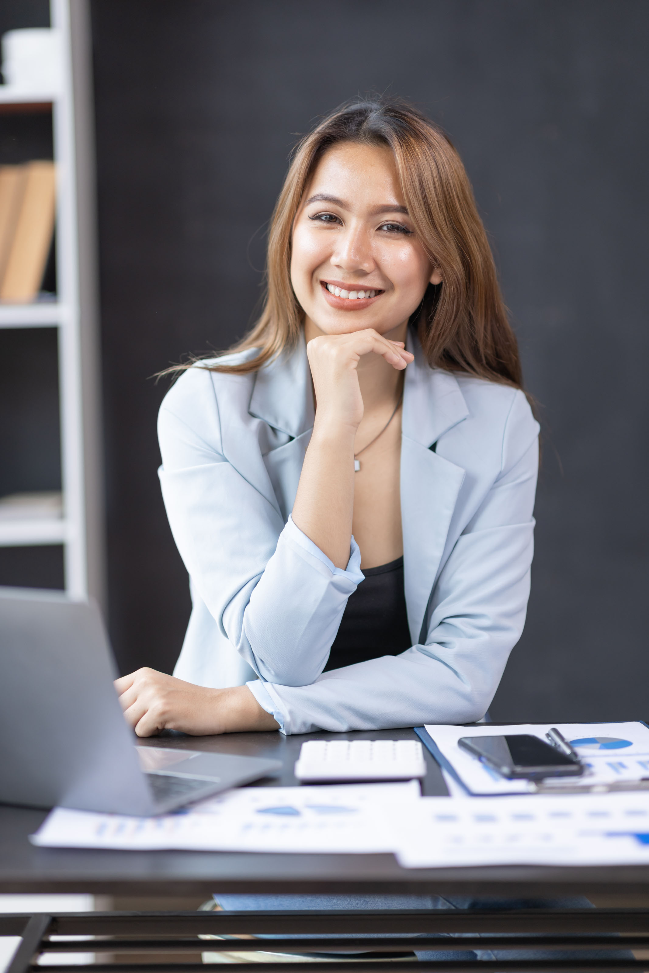 Young businesswoman resting her chin on her hand at a desk