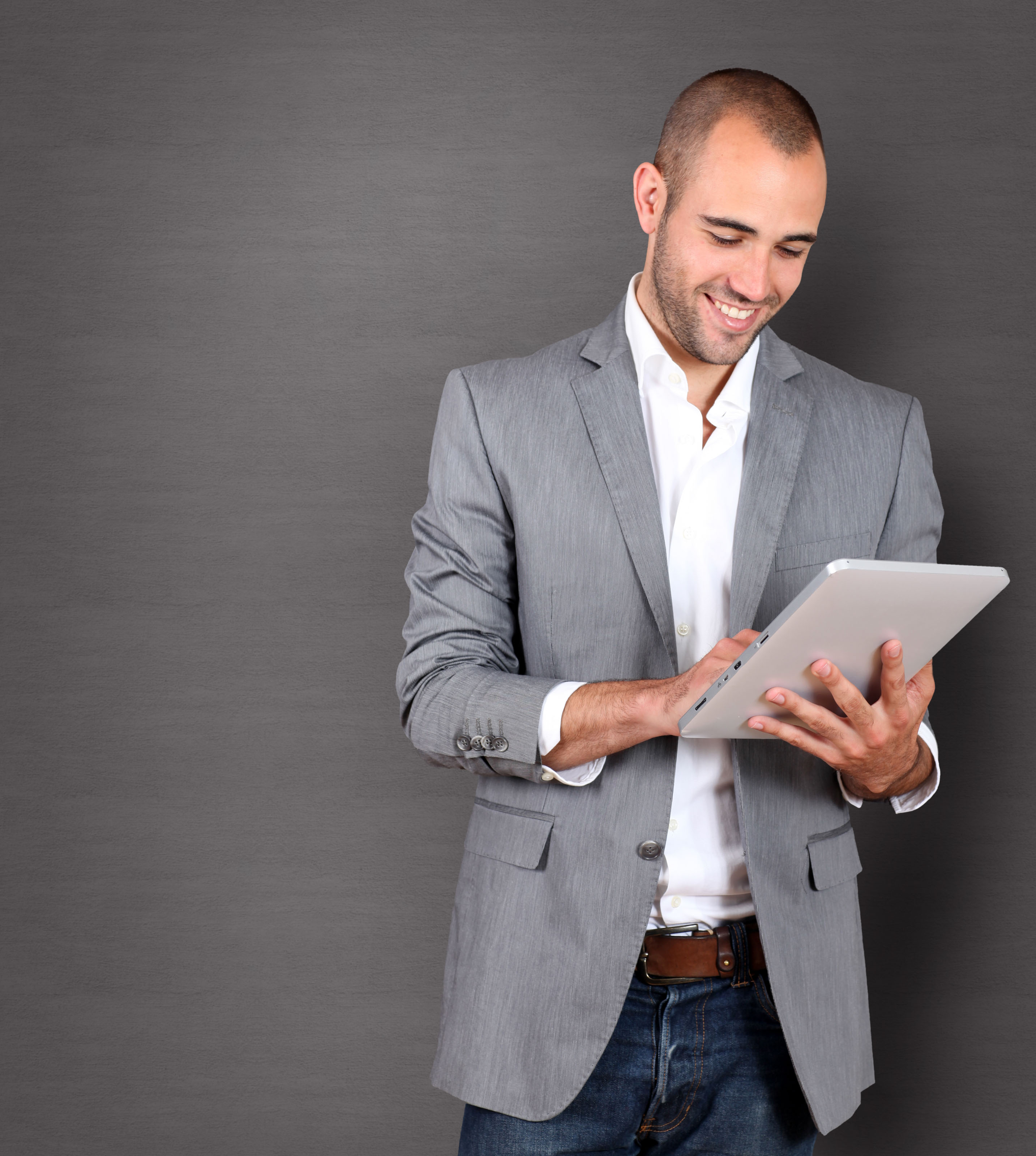 Young businessman in a gray blazer using a tablet