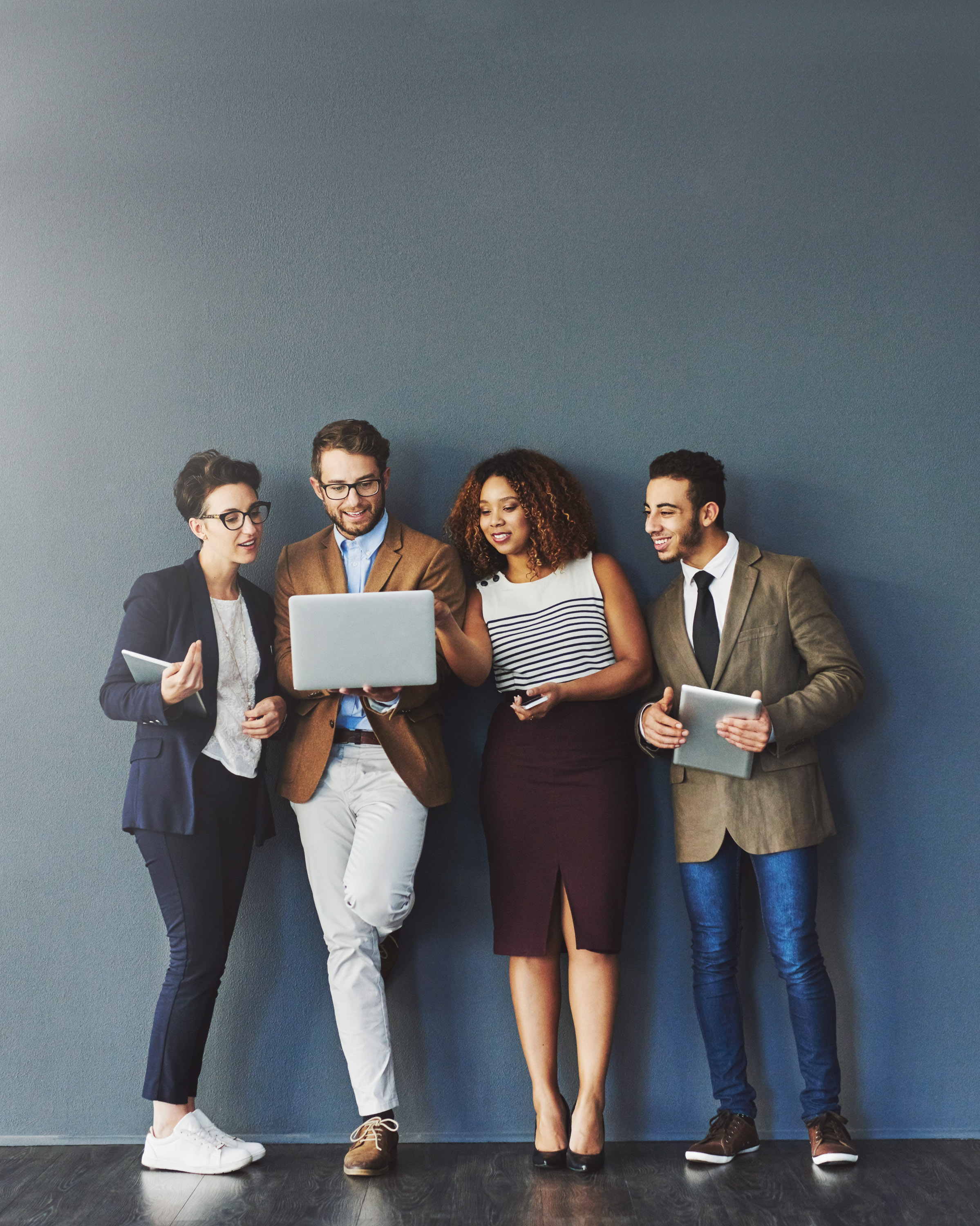Four business colleagues in a row looking at a laptop