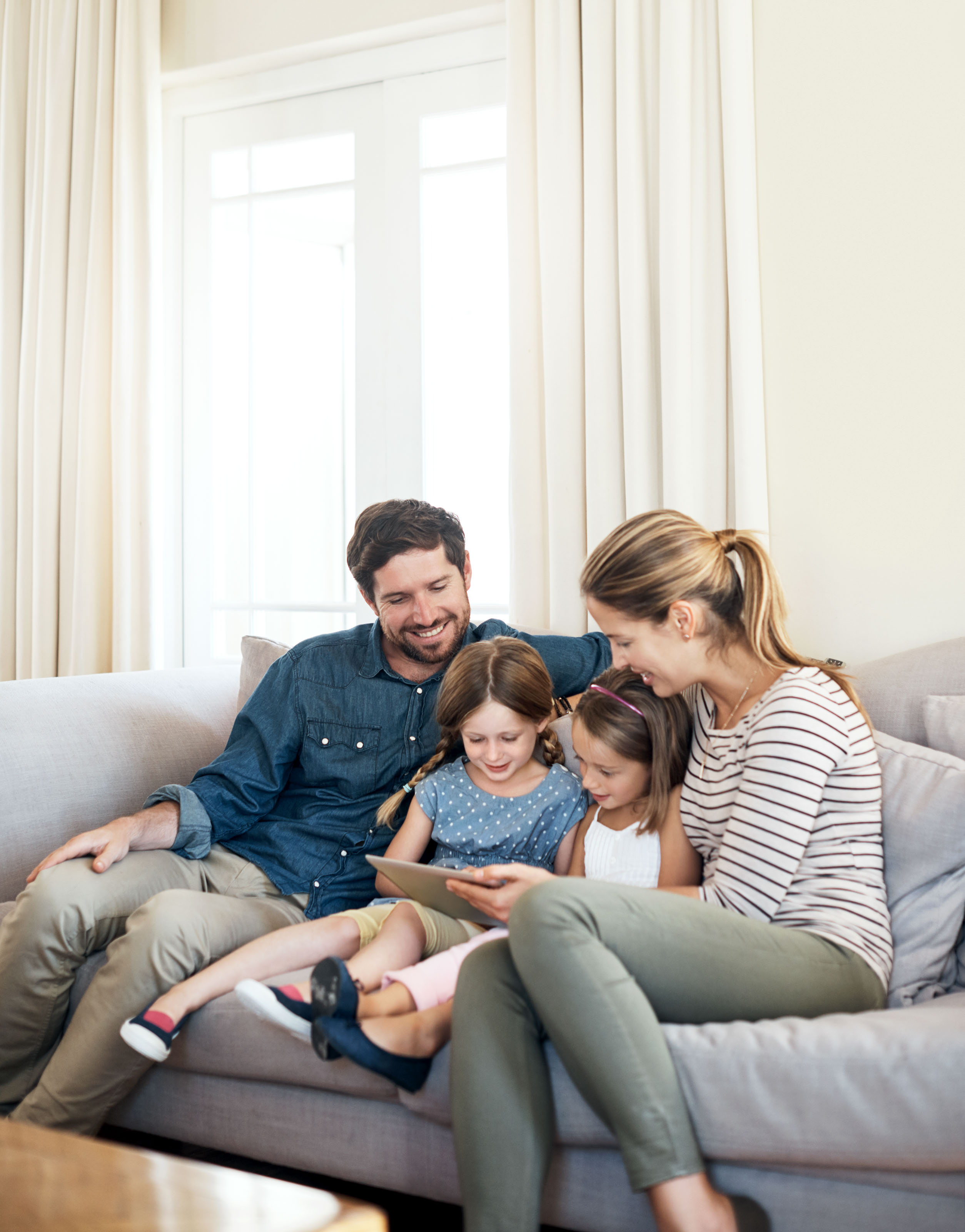 Family of four on a sofa sharing a tablet