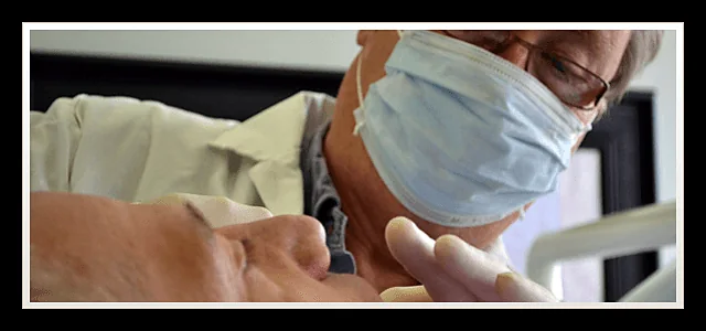 Close-up of the clinician in a mask and glasses during an examination at Southland Denture Clinic