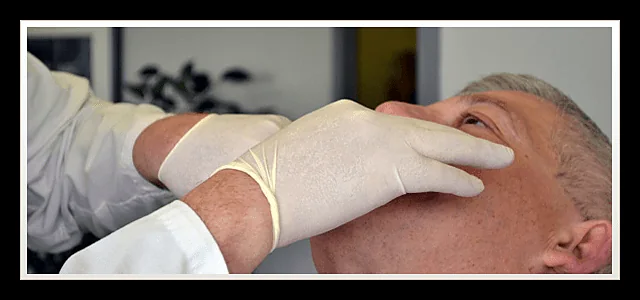 Close-up of a clinician's gloved hands during a jaw examination at Southland Denture Clinic