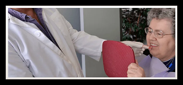 Patient holding a hand mirror while the clinician explains her denture fit at Southland Denture Clinic