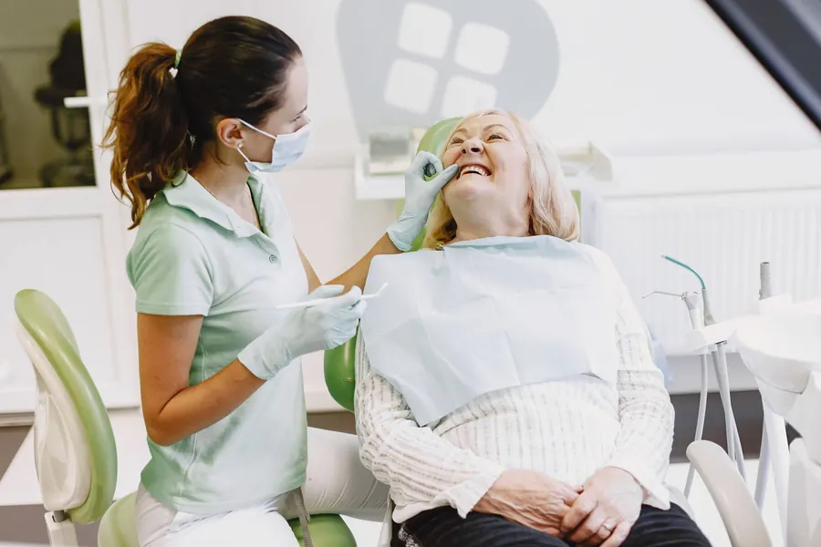 Dental professional examining a smiling senior patient (stock photo)