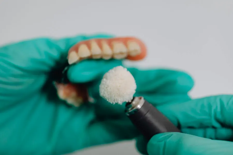 Gloved hands polishing a denture (stock photo)