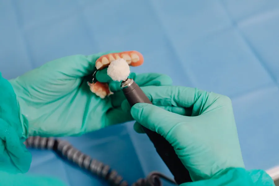 Dental technician working on a denture with a precision tool (stock photo)