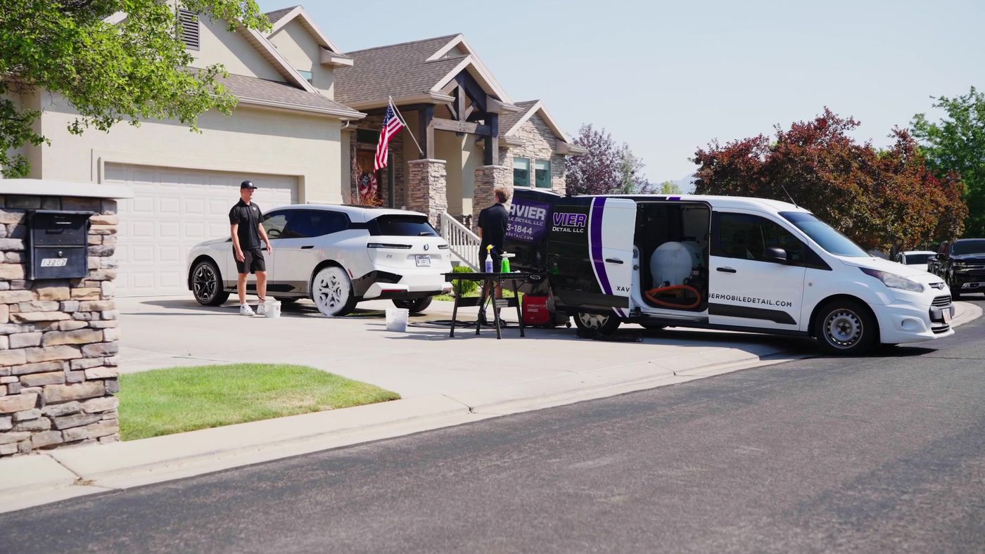 Xavier Auto Care van detailing a white SUV in a Utah driveway