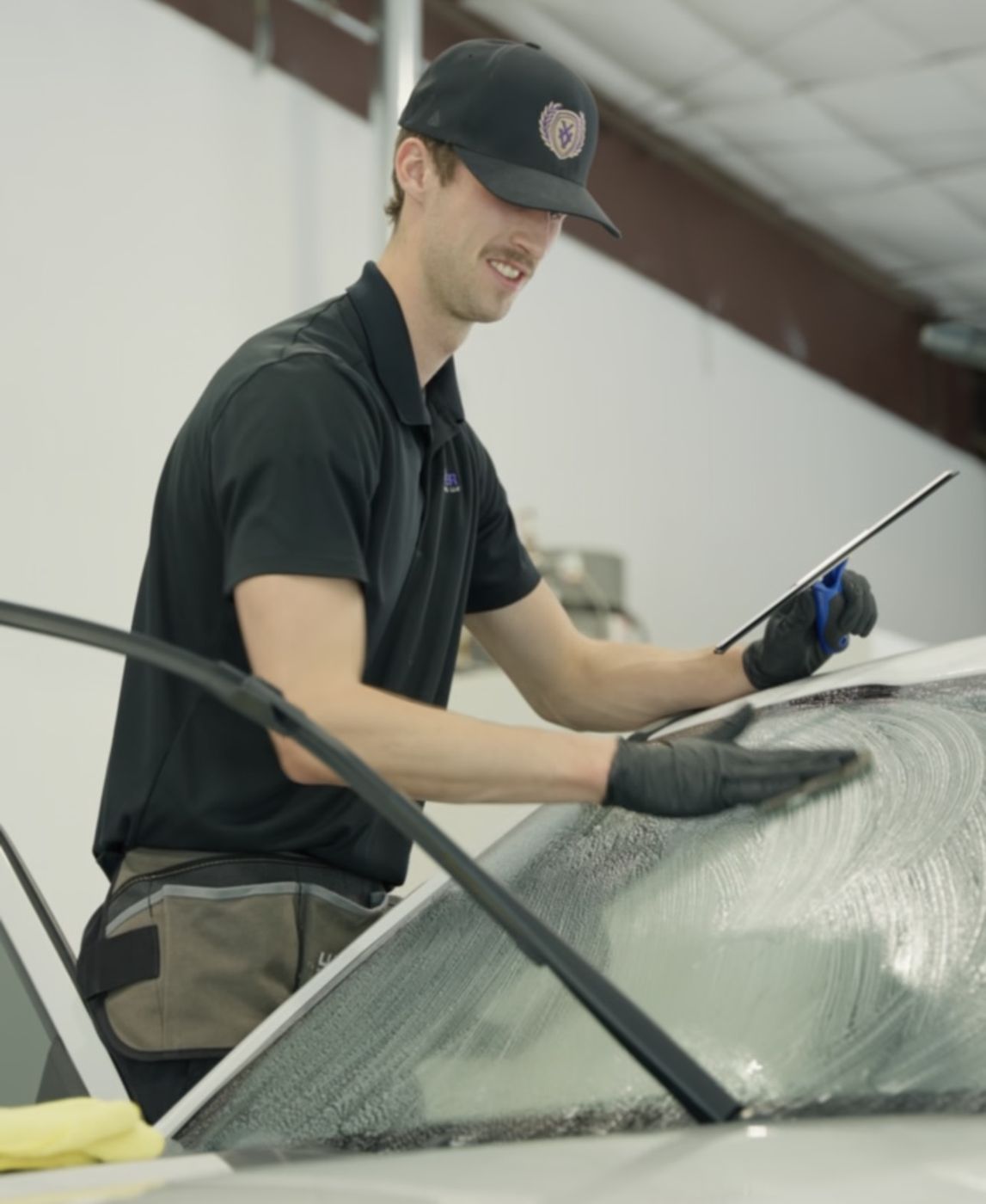 Installer shaping ceramic heat film on a windshield