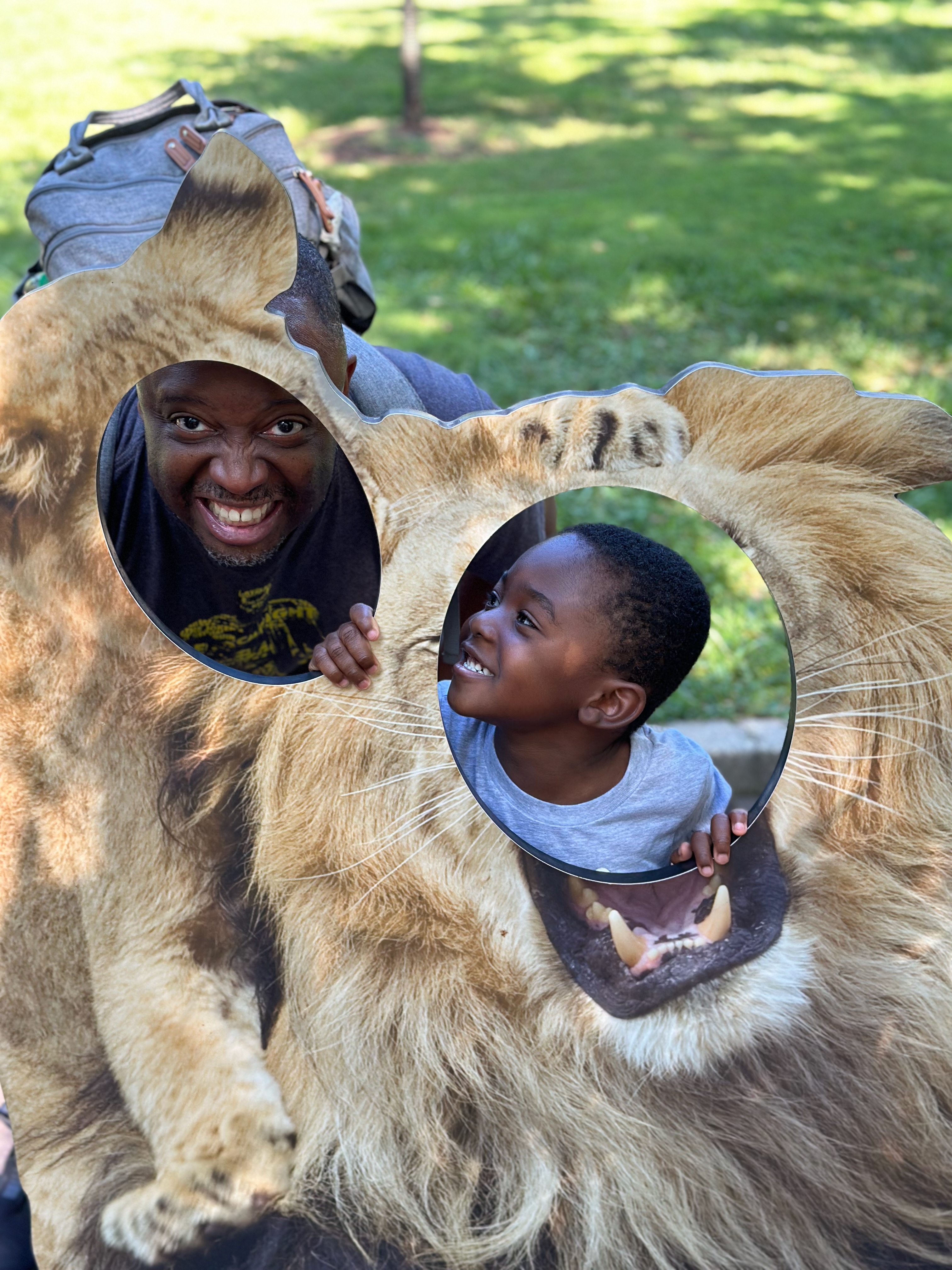  father and young son laughing inside lion face photo cutout at National Zoo DC