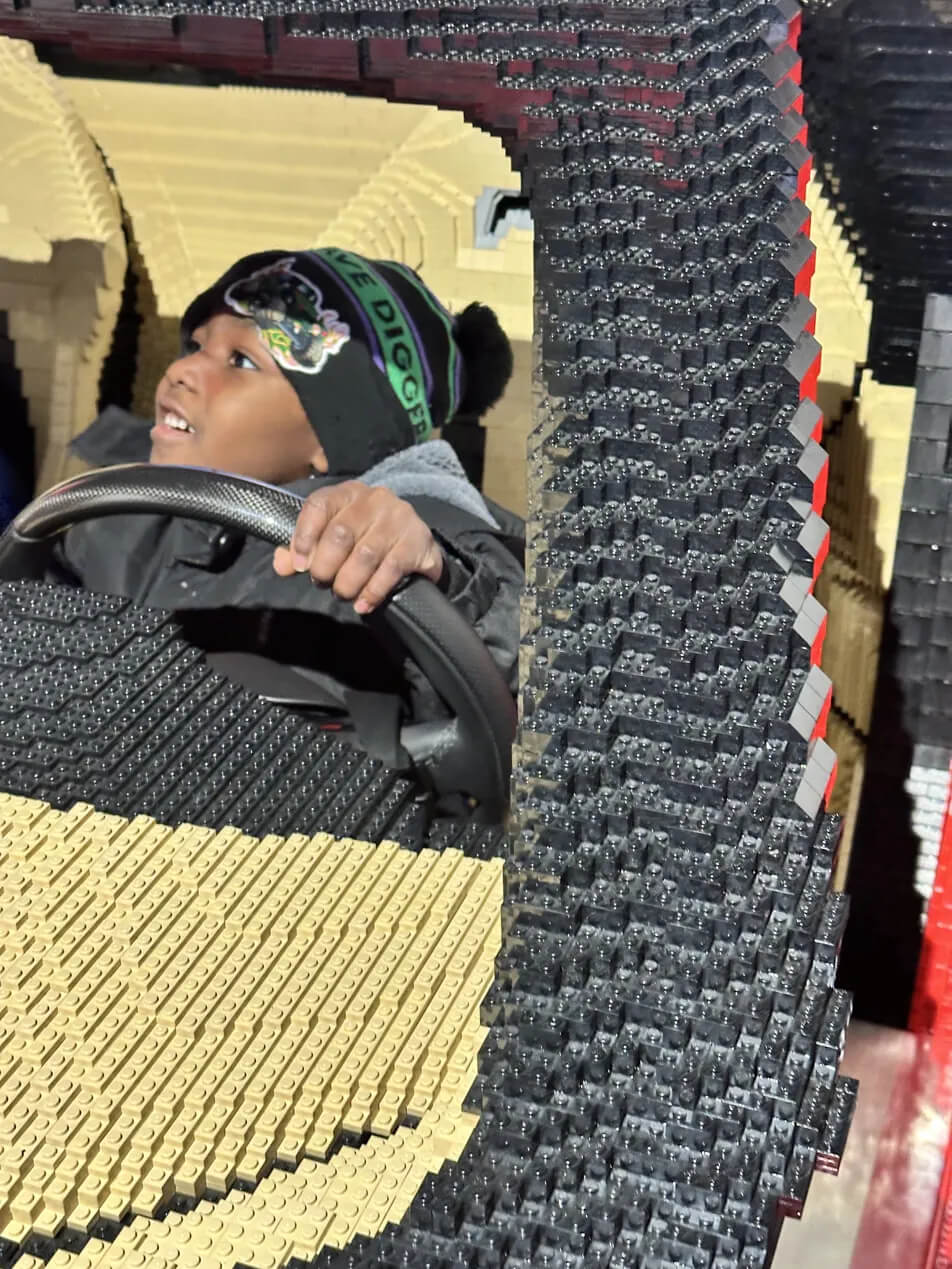 Black boy gripping the steering wheel inside the giant LEGO Ferrari built with 500000 bricks at LEGOLAND New York