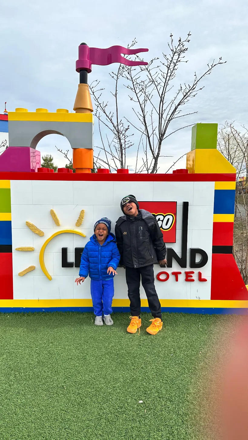 Two brothers laughing in front of the LEGOLAND New York Hotel sign in Goshen NY
