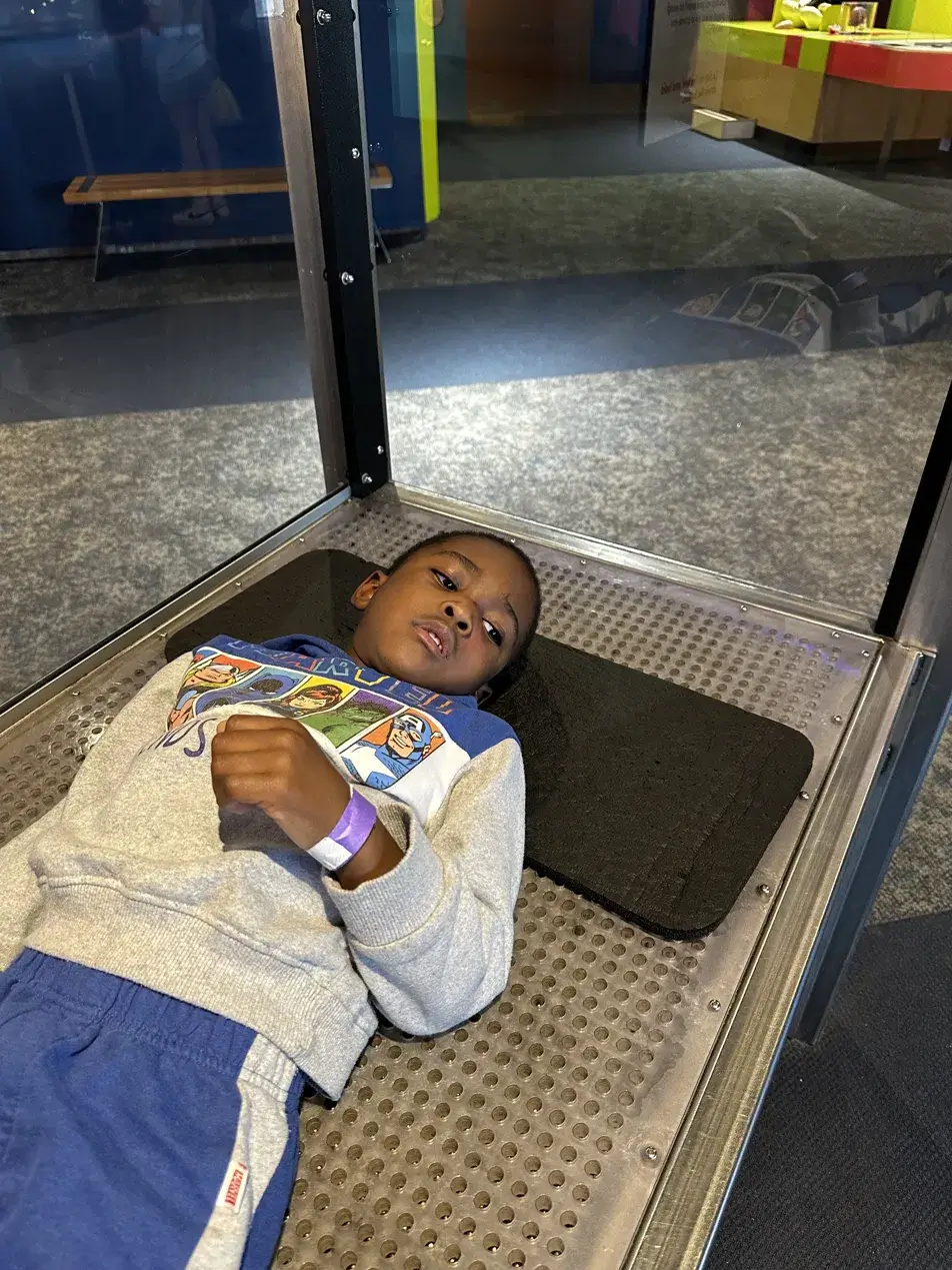 Young Black boy lying on an interactive pressure exhibit at Maryland Science Center in Baltimore