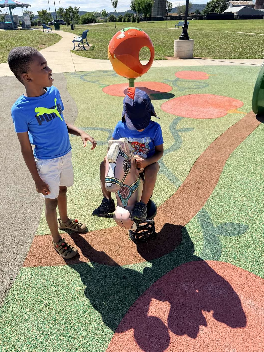 Two boys playing together on a spring horse and orange spinner at Sophie and Madigan's inclusive playground in Frederick, Maryland Two boys playing together on a spring horse and orange spinner at Sophie and Madigan's inclusive playground in Frederick, Maryland