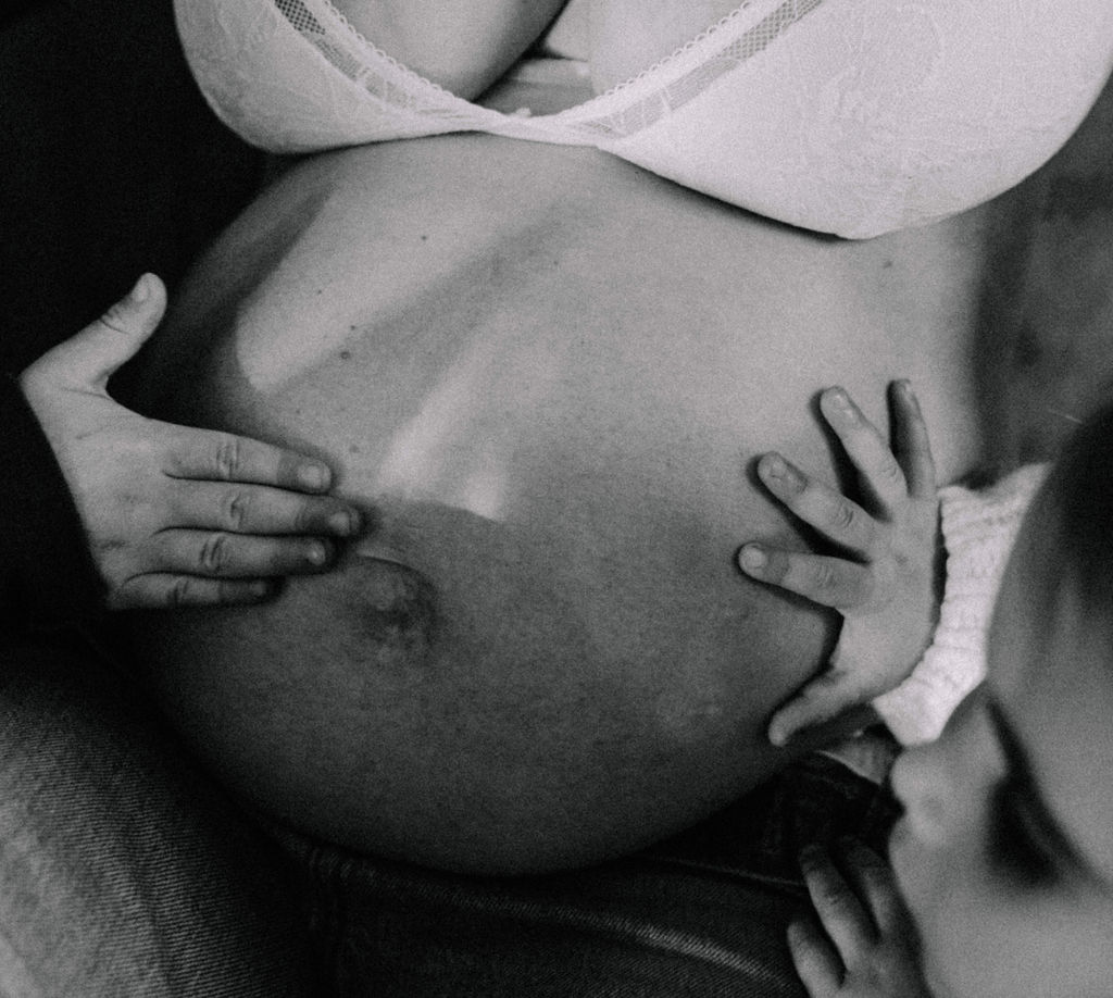 Pregnant belly with children's hands
