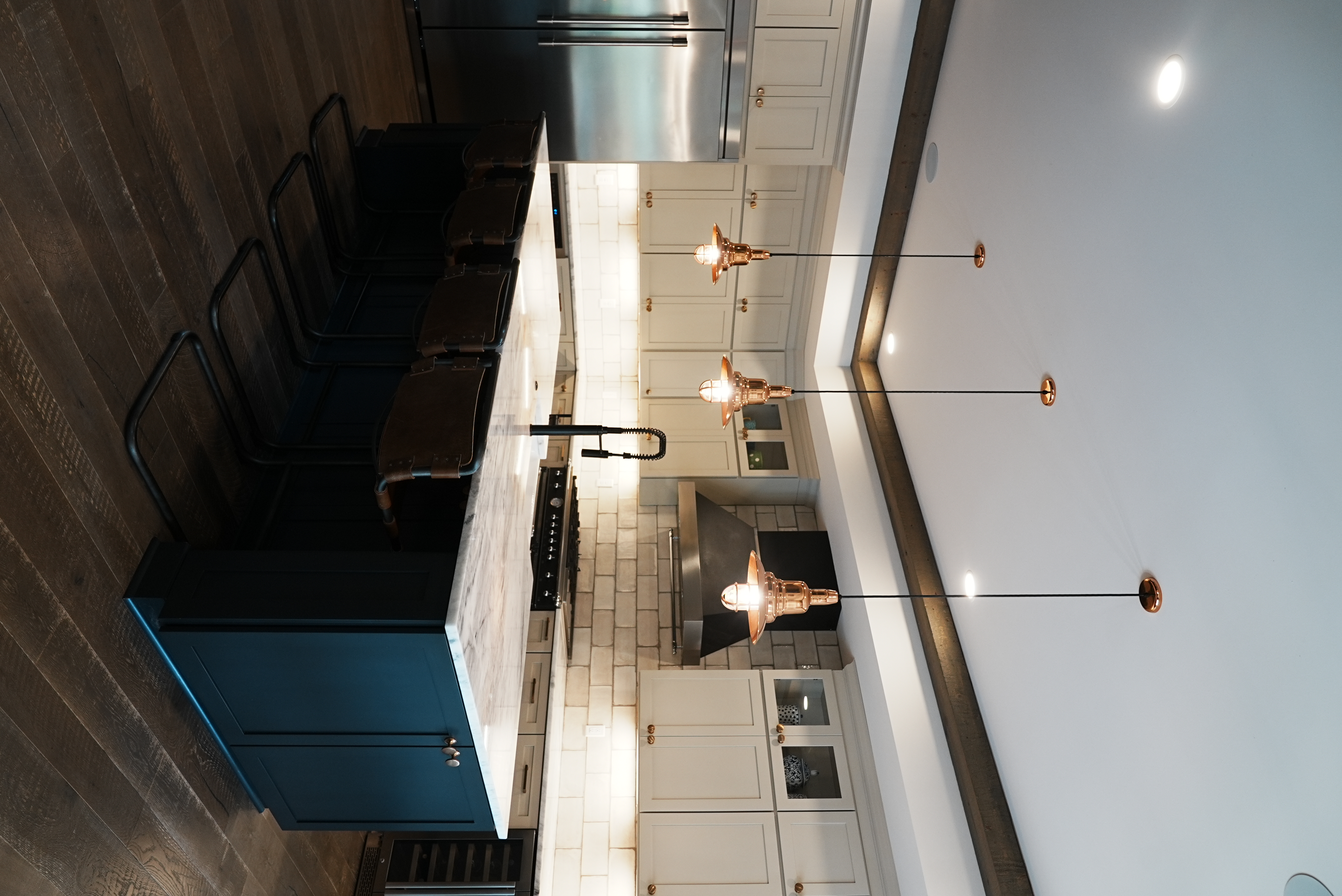Kitchen island with copper pendant lights and navy cabinetry