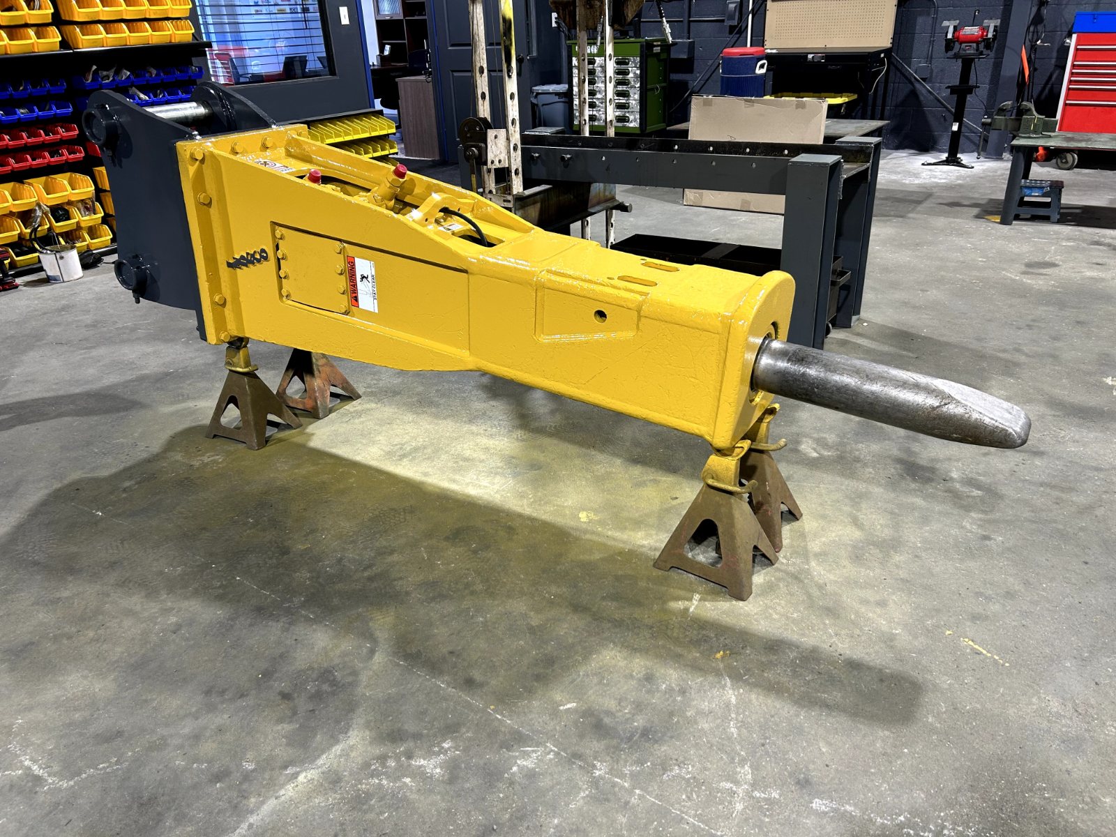 Yellow hydraulic hammer on stands in the workshop