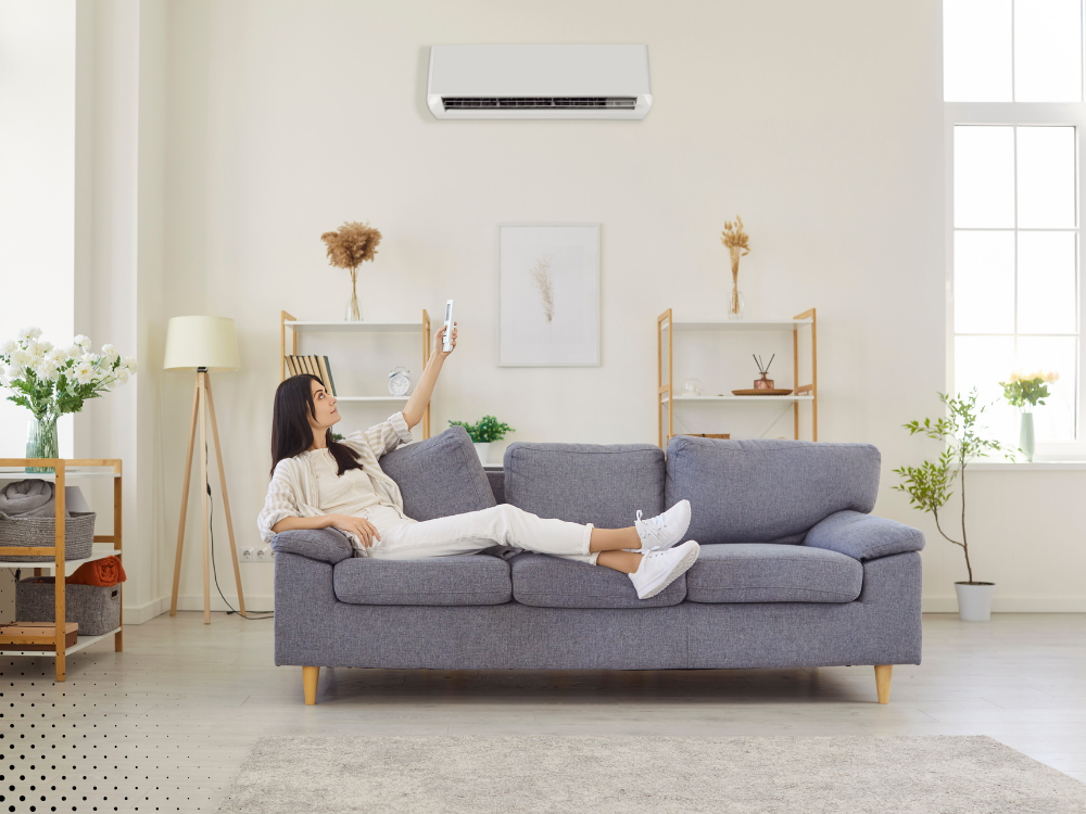 Homeowner relaxing on couch under wall-mounted air conditioner showing efficient cooling after professional home inspection in Texas