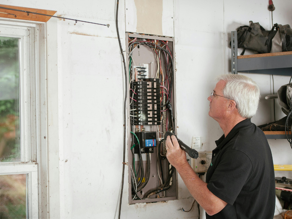 Home inspector examining electrical panel wiring and circuit breakers during a home inspection in Dallas Fort Worth Texas